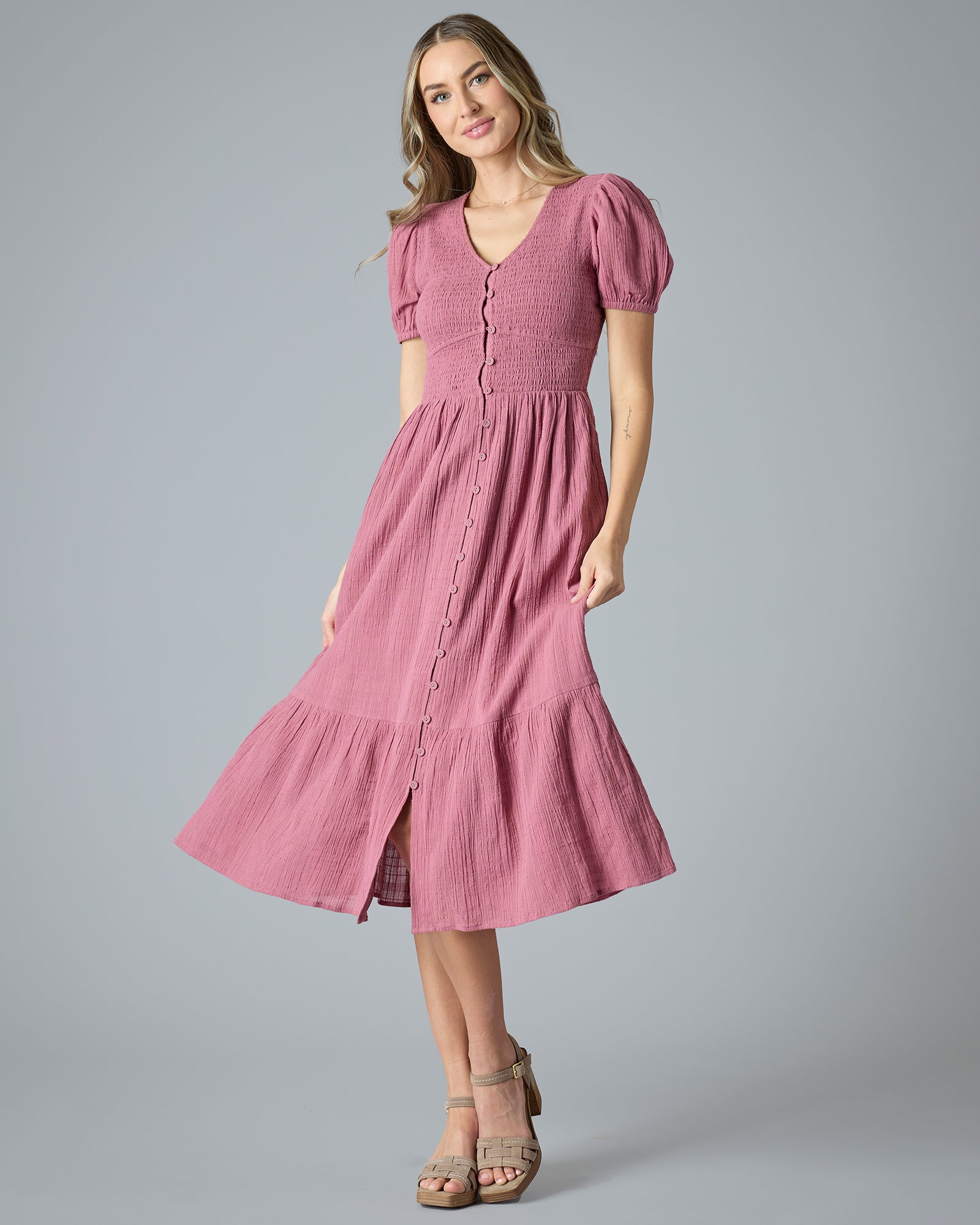 Woman in a pink short sleeve, v-neck, midi-length dress with buttons down the front