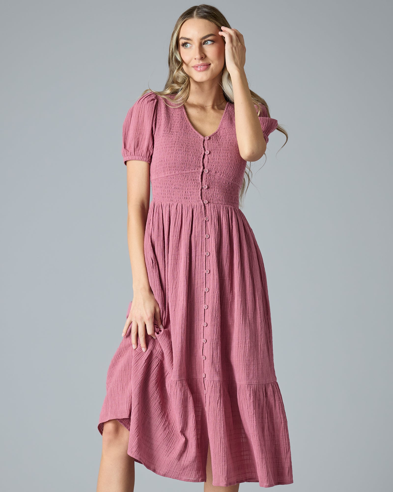 Woman in a pink short sleeve, v-neck, midi-length dress with buttons down the front