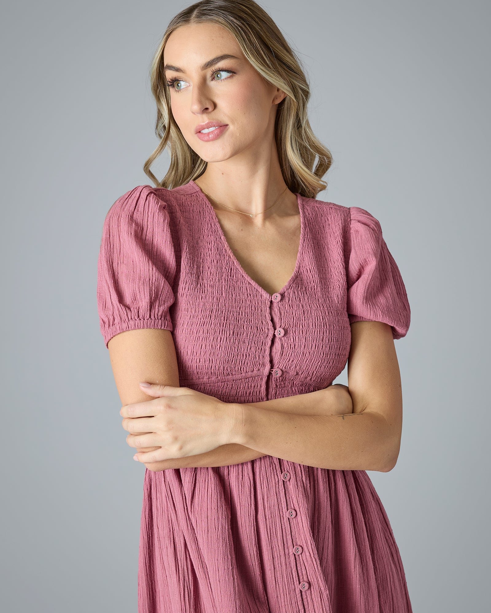 Close up of woman in a pink short sleeve, v-neck, midi-length dress with buttons down the front