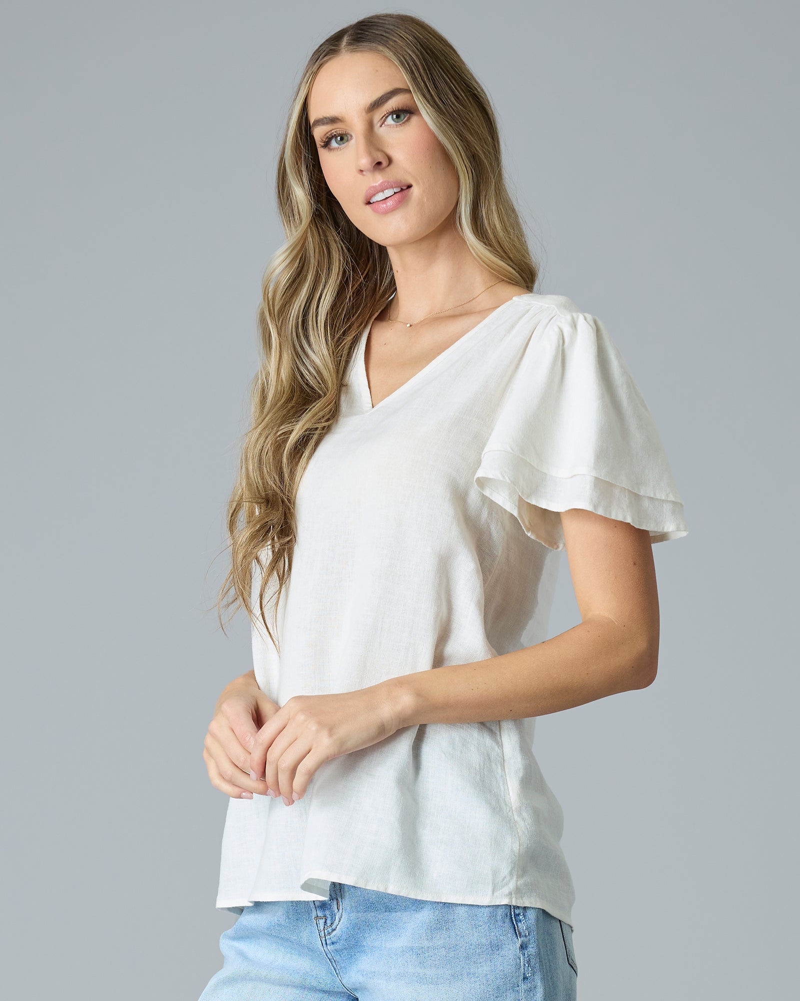 Woman in cream colored short sleeve, v-neck linen blouse
