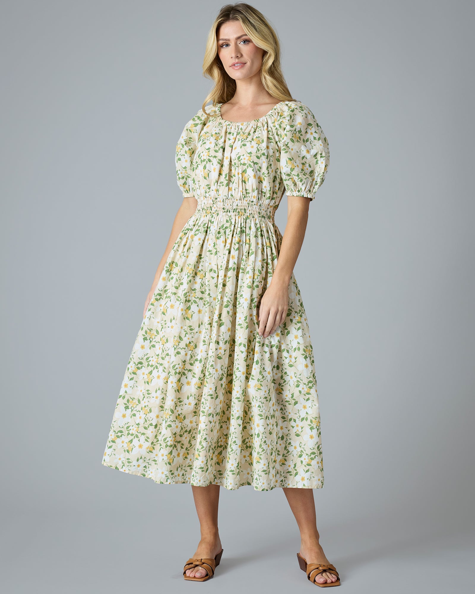 Woman in a green and yellow floral print dress that is midi-length with short sleeves