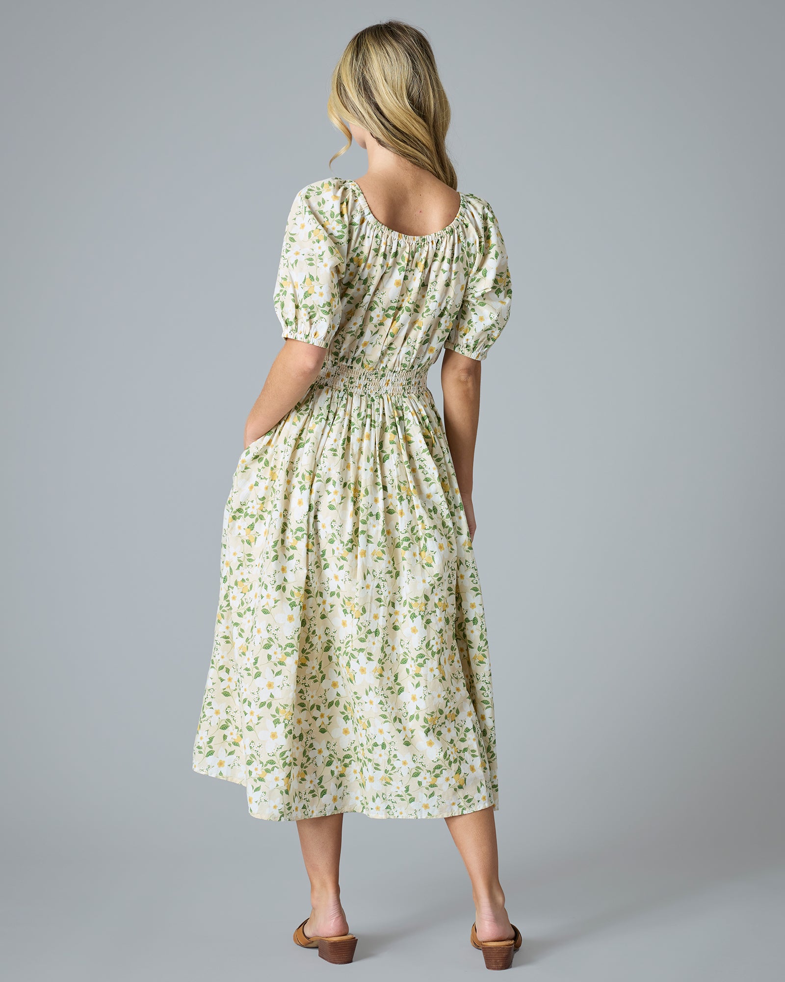 Woman in a green and yellow floral print dress that is midi-length with short sleeves