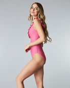 Woman in a one-piece v-neck ruffle pink swimsuit.