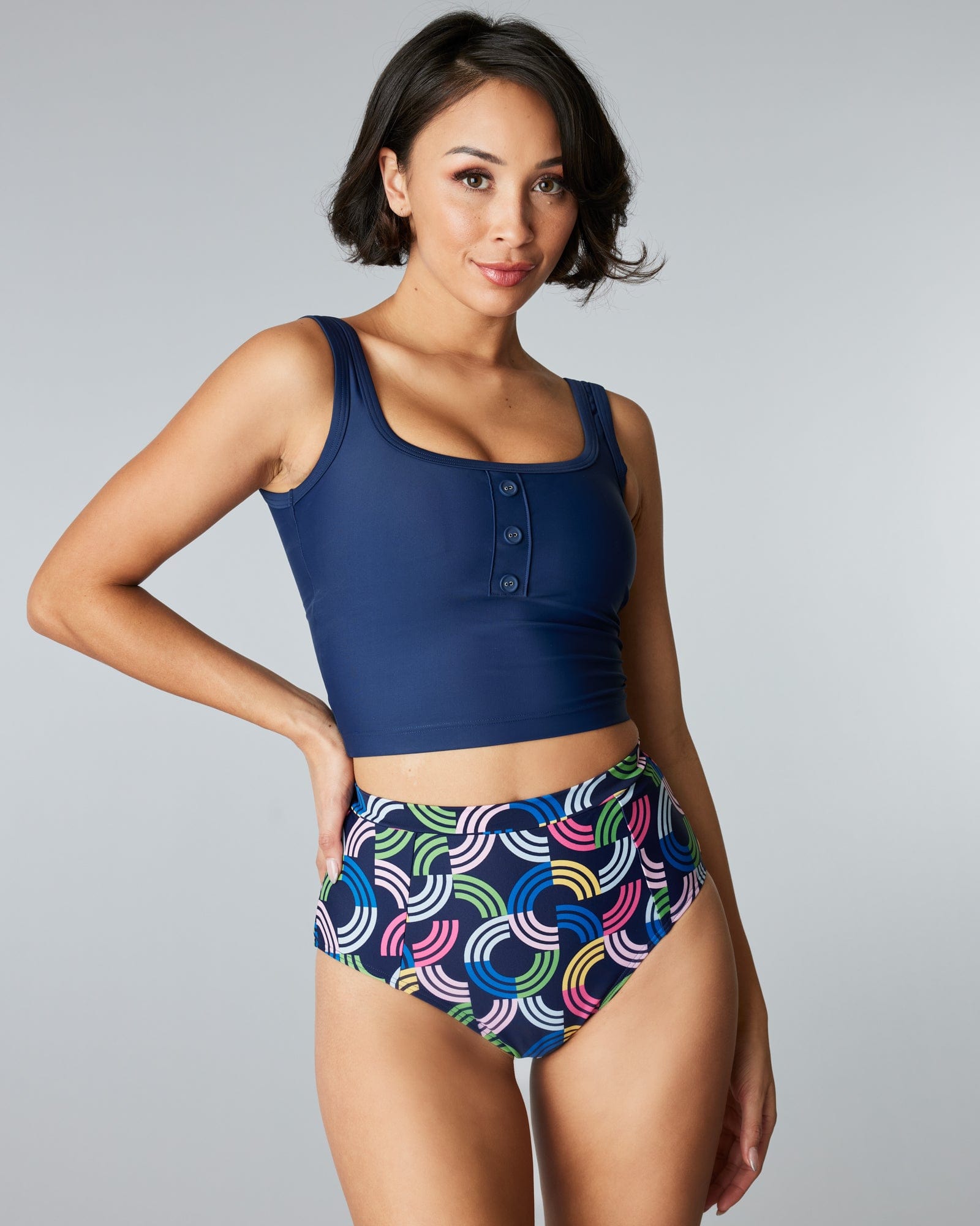 Woman in a two-piece swimsuit with a rainbow print and patterned top & bottom.