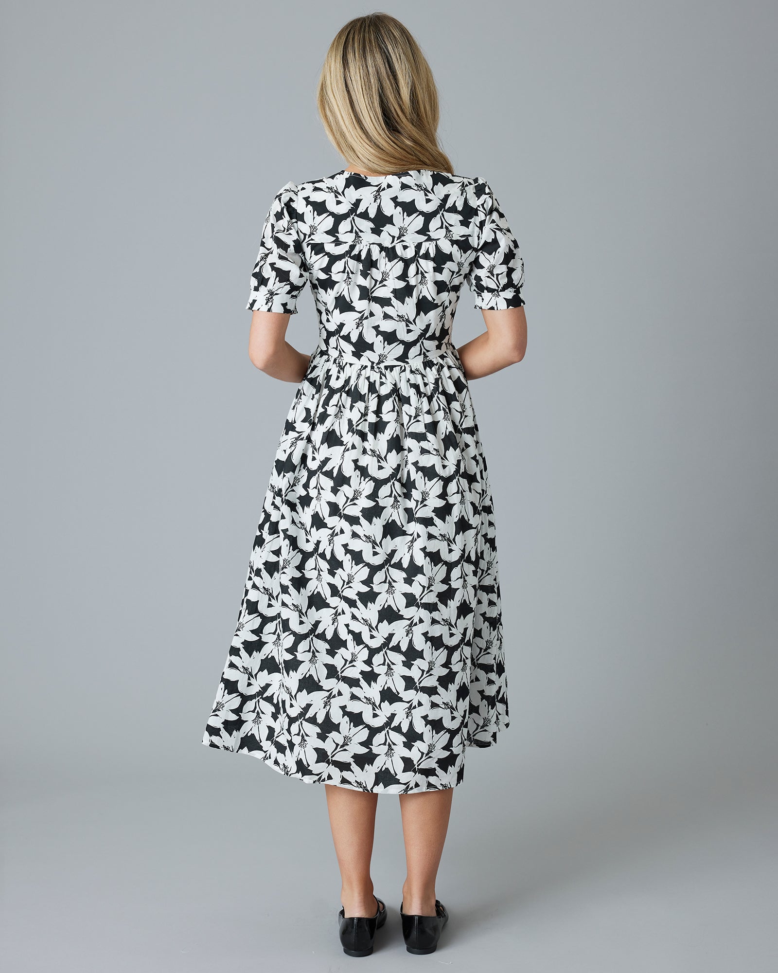 Woman in a black and white floral short sleeve midi-length dress