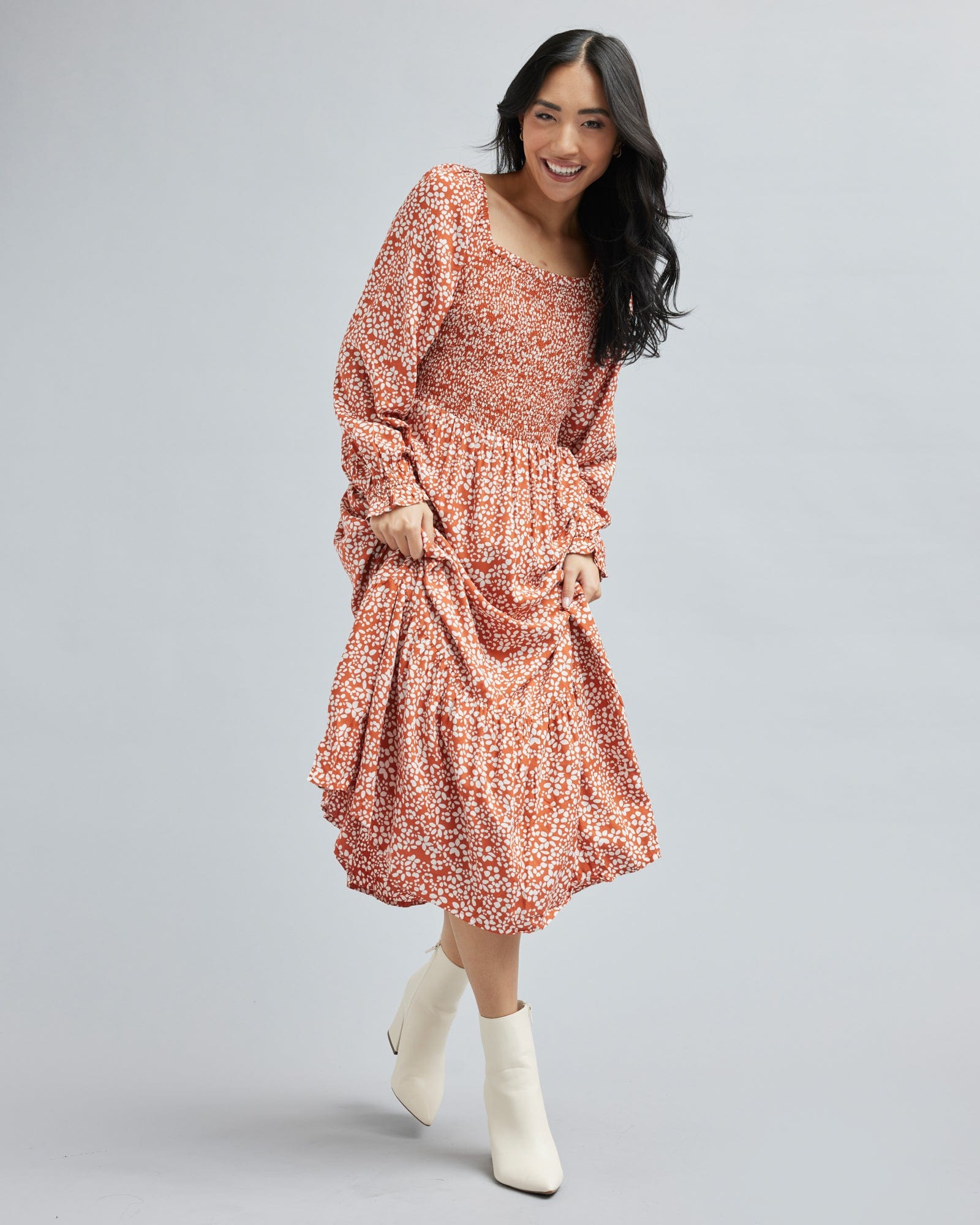 Woman in a long sleeve, midi-length, orange and white floral dress