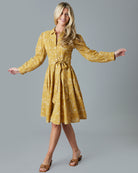 Woman in a long sleeve, collared, knee-length, yellow dress