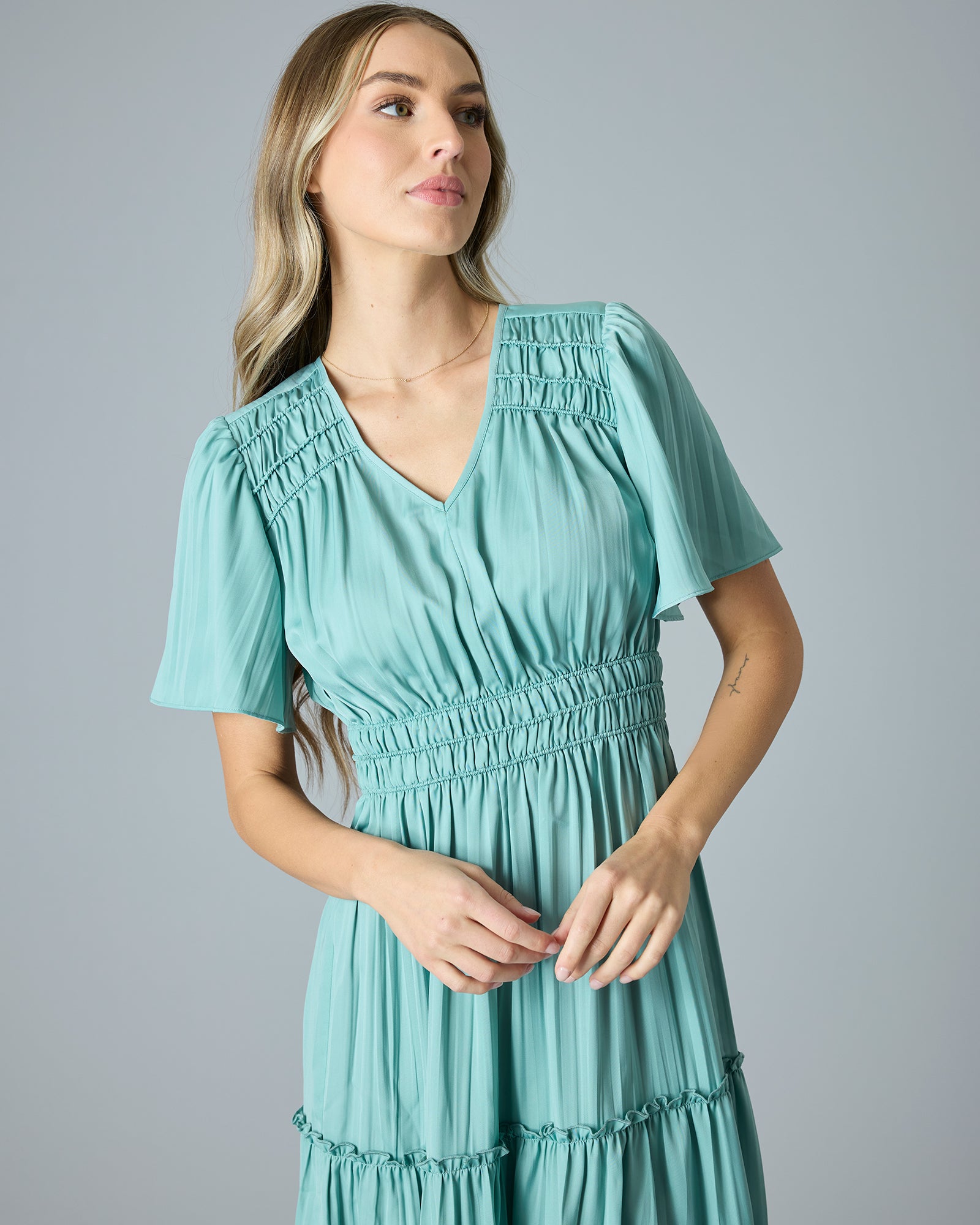 Woman in a green/blue short sleeve, v-neck, maxi length dress