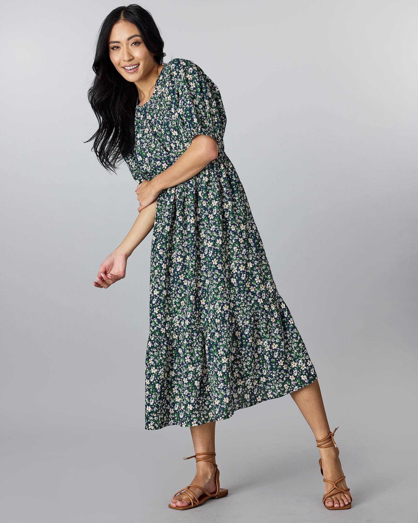 Woman in a blue and green floral, short sleeved, midi-length dress.