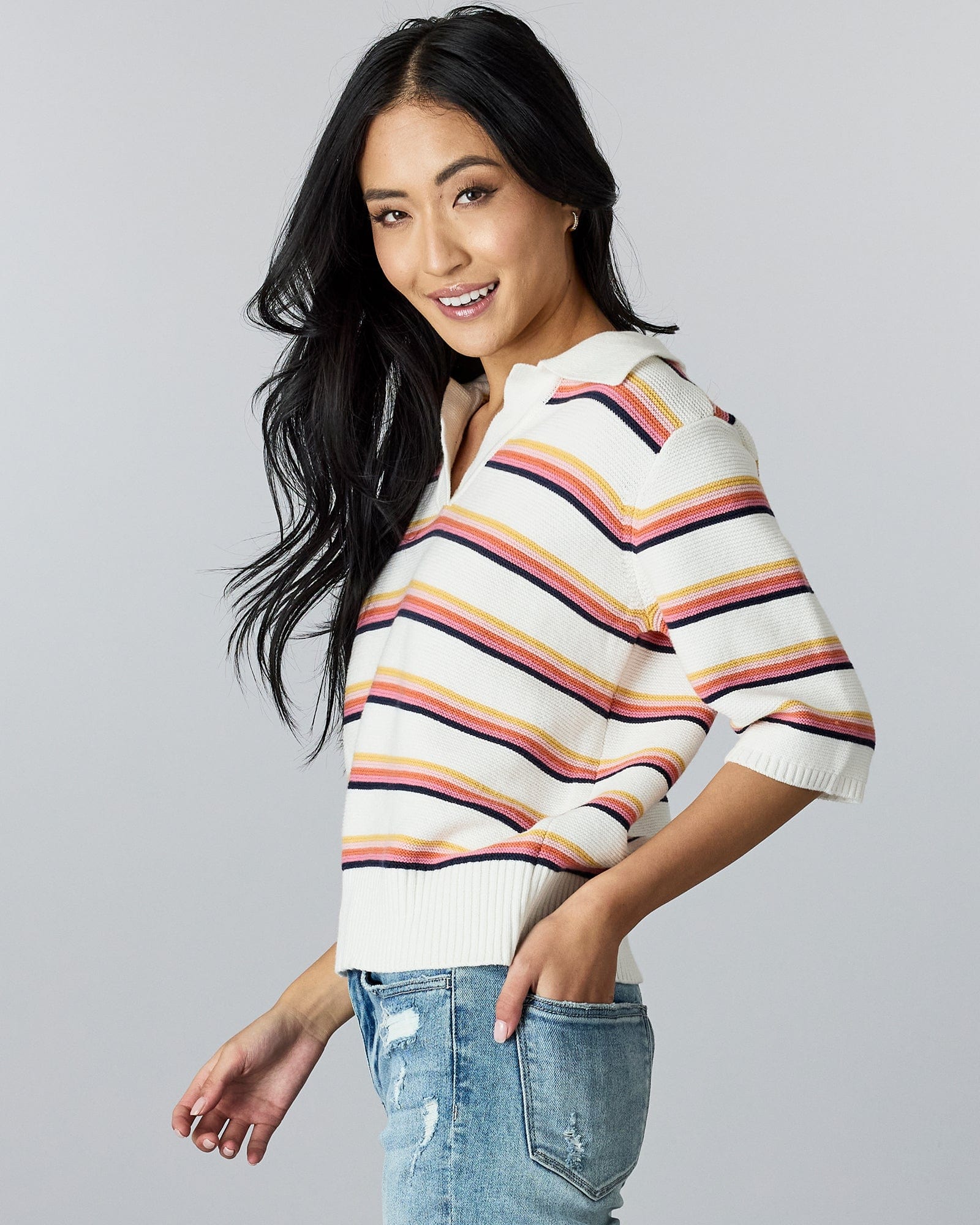 Woman in a half-sleeved, rainbow striped sweater with v-neck and collar.