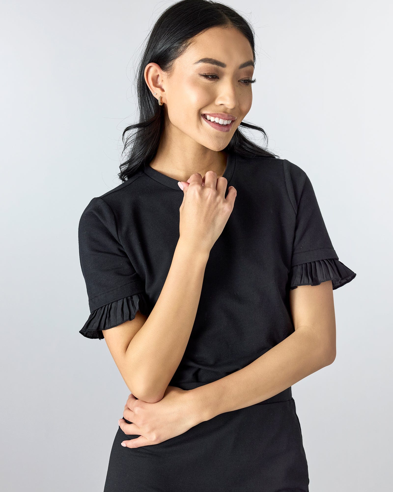 Woman in a black short sleeved top with ruffles on bottom of sleeve hem.