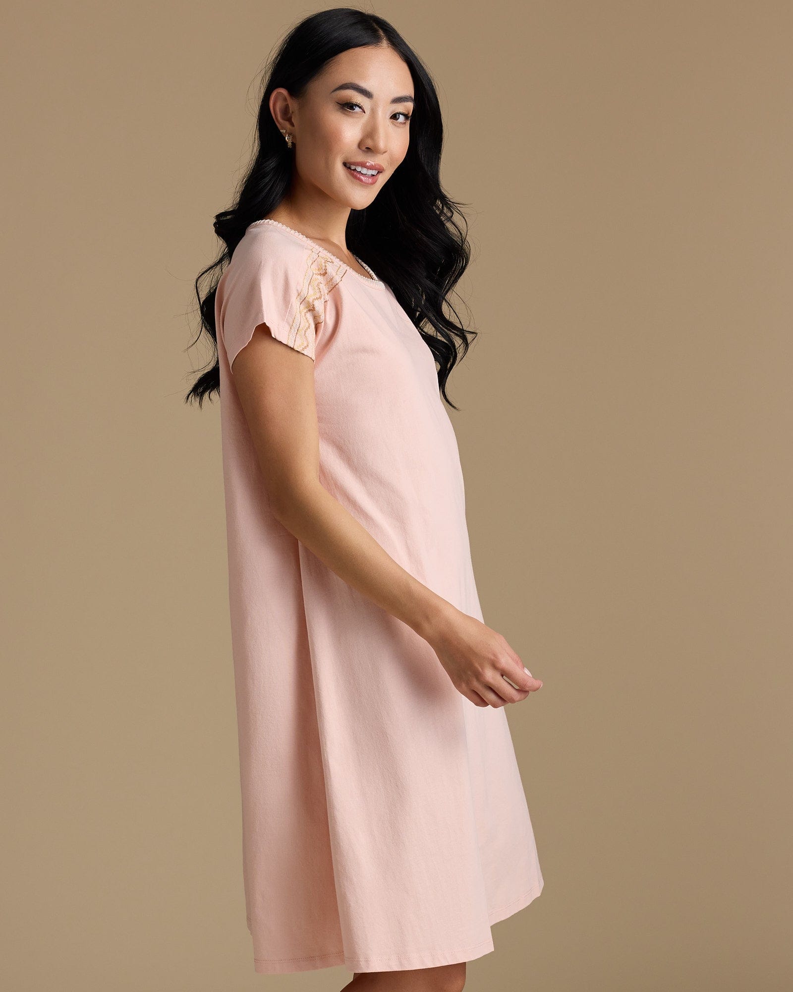 Woman with a short sleeve, knee-length pink dress with embroidery on shoulders