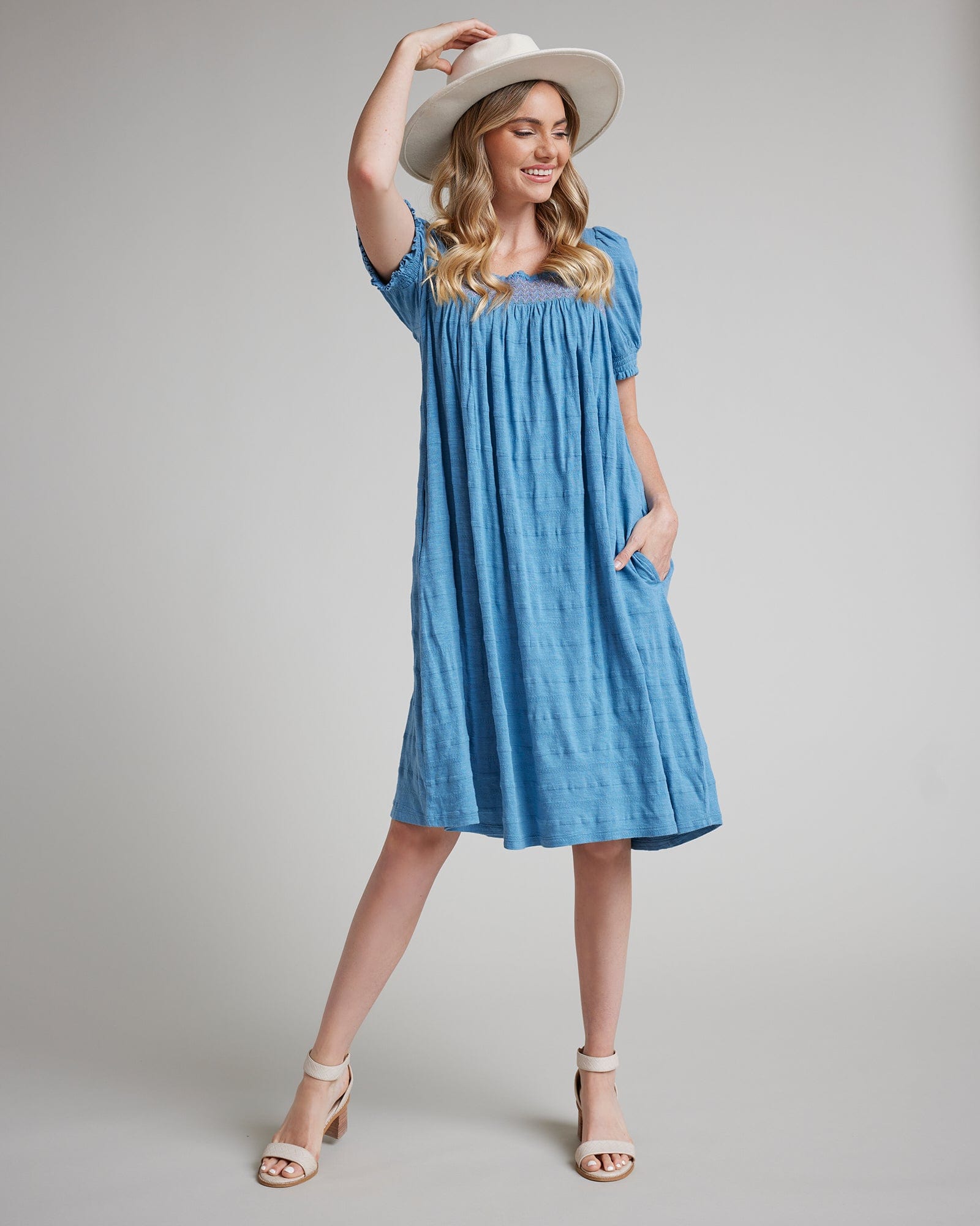 Woman in a short sleeve, knee-length, blue dress with pockets