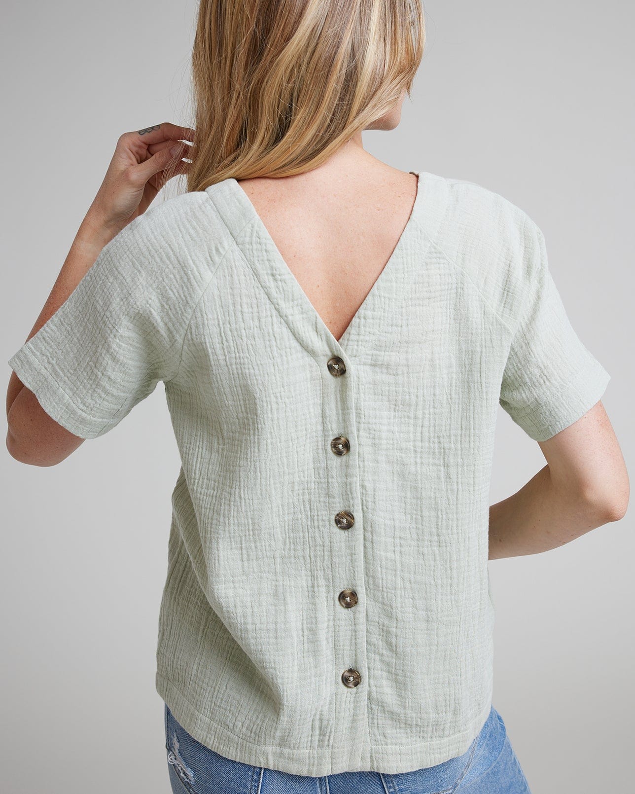 Woman in a green blouse with short sleeves and buttons down the back