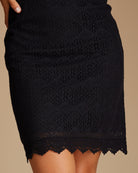 Woman in a short sleeve, scalloped hem, knee-length, black dress
