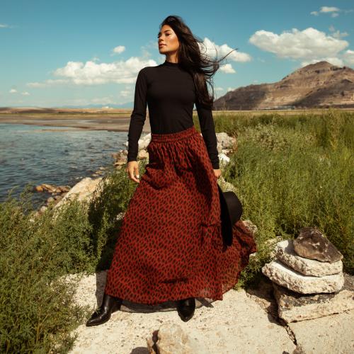 A women in a black long sleeve and animal printed skirts. Shop skirts.  