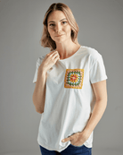 Woman in a white t-shirt with short sleeves and a crochet patch on chest