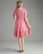 Woman in a short sleeve, knee-length, smocked bodice, pink dress