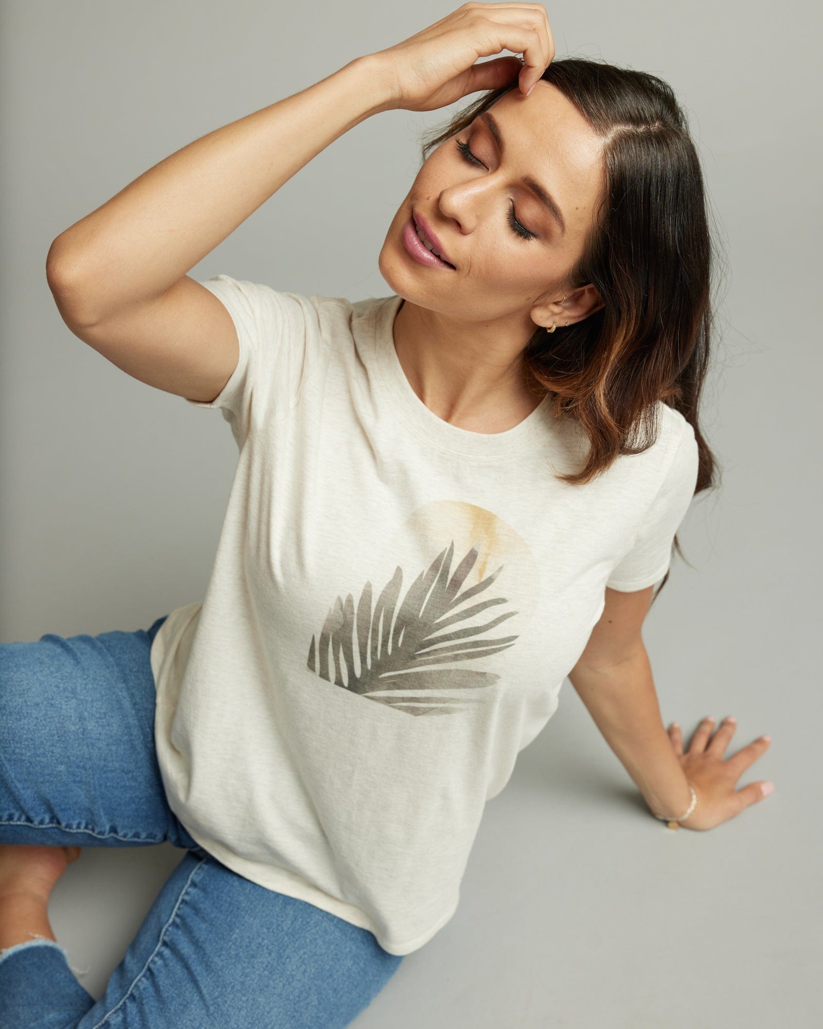 Woman in a short sleeve white graphic tee with a moon and plant design on front