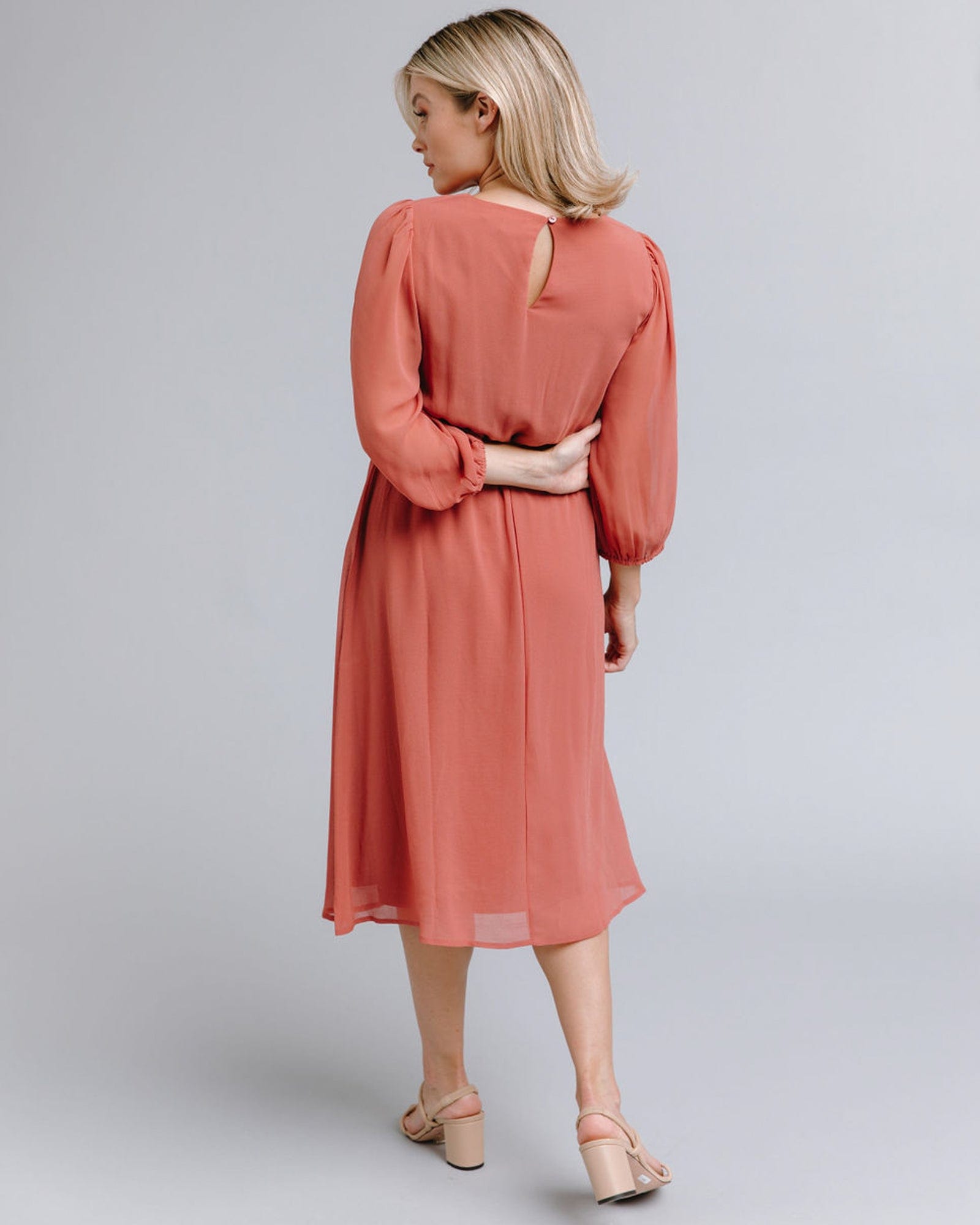 Woman in a long sleeve, knee-length, orange dress