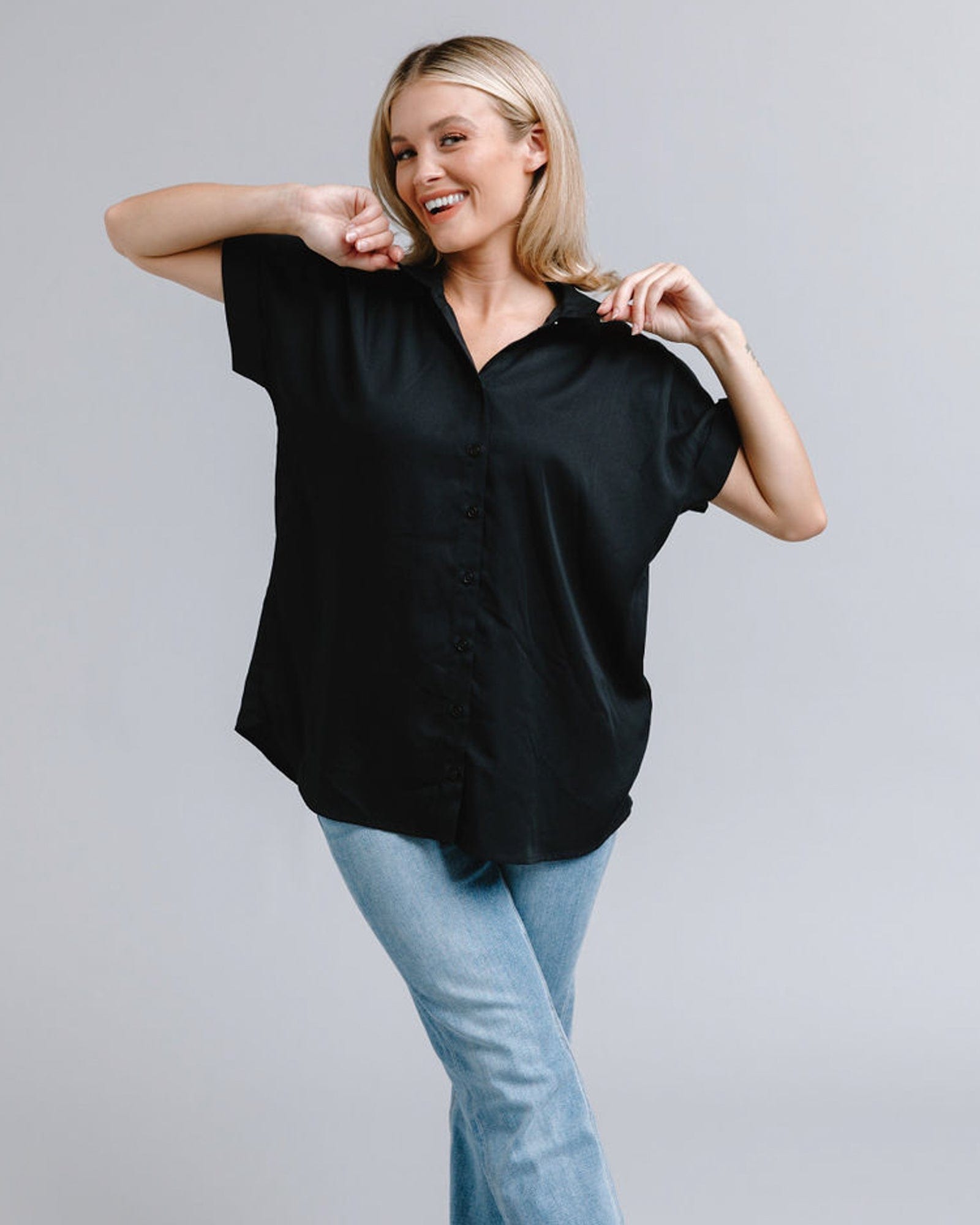 Woman in a short sleeve, collared, loose fitting black top