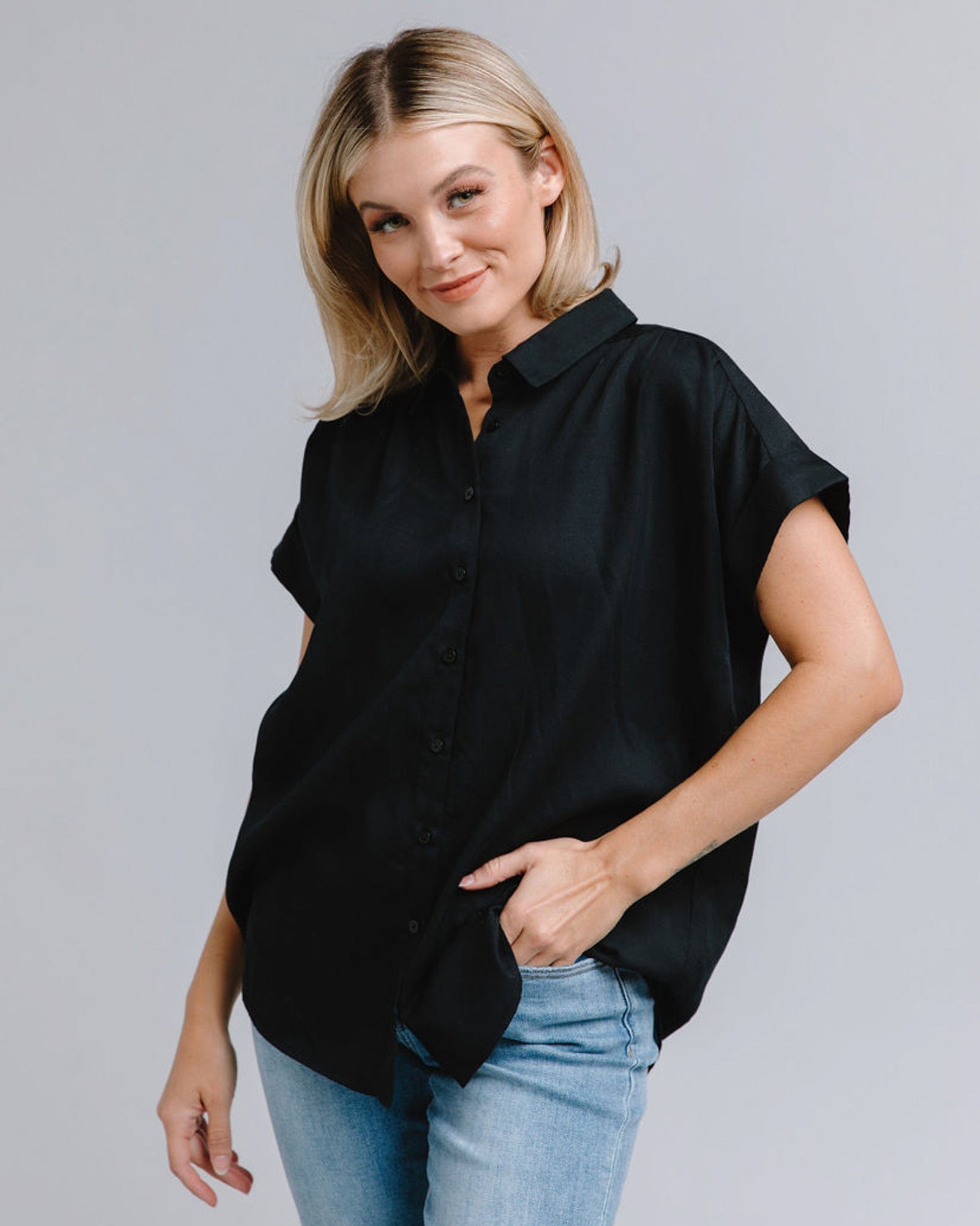Woman in a short sleeve, collared, loose fitting black top