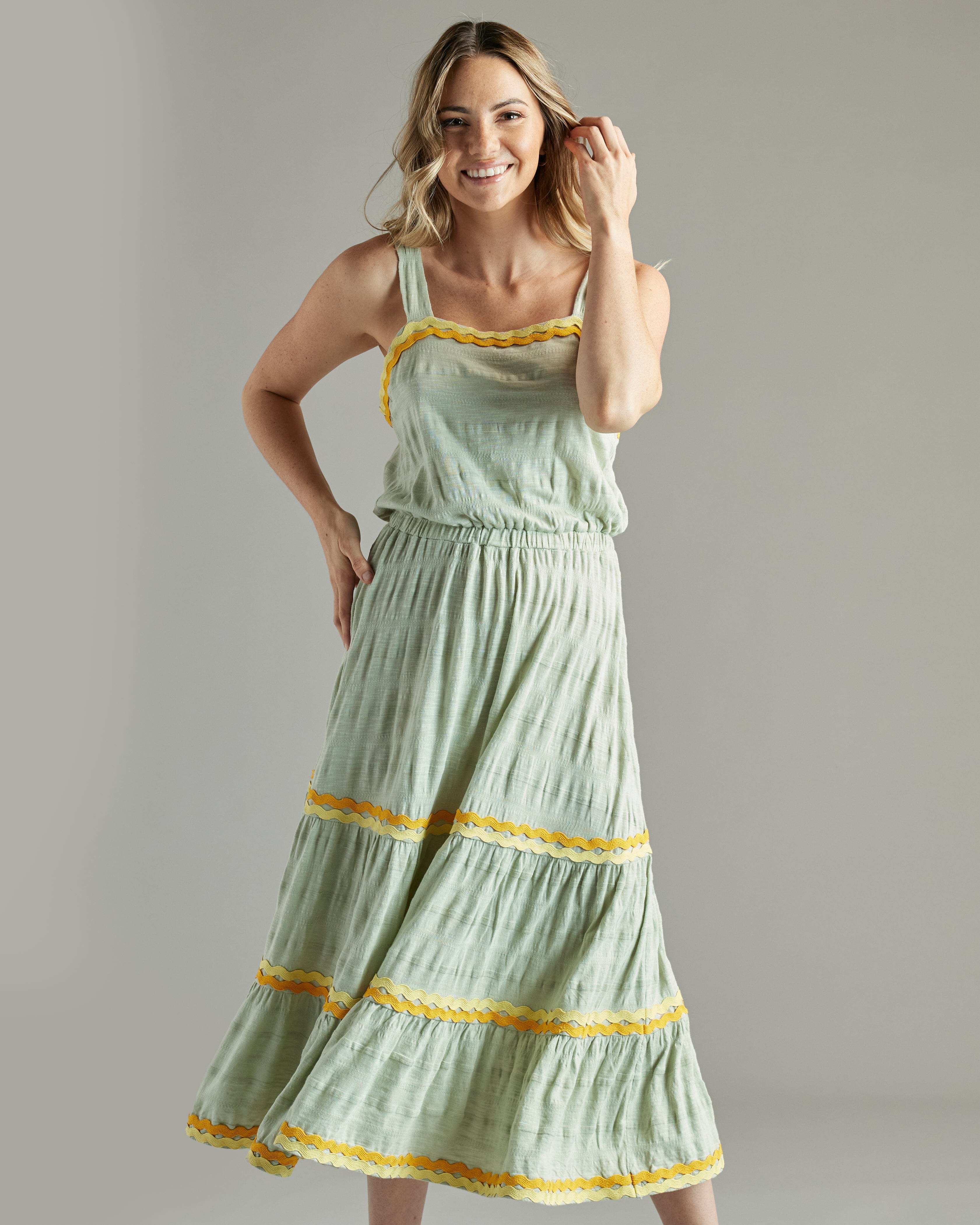 Woman in a sleeveless, midi-length green dress with orange and yellow lace accents