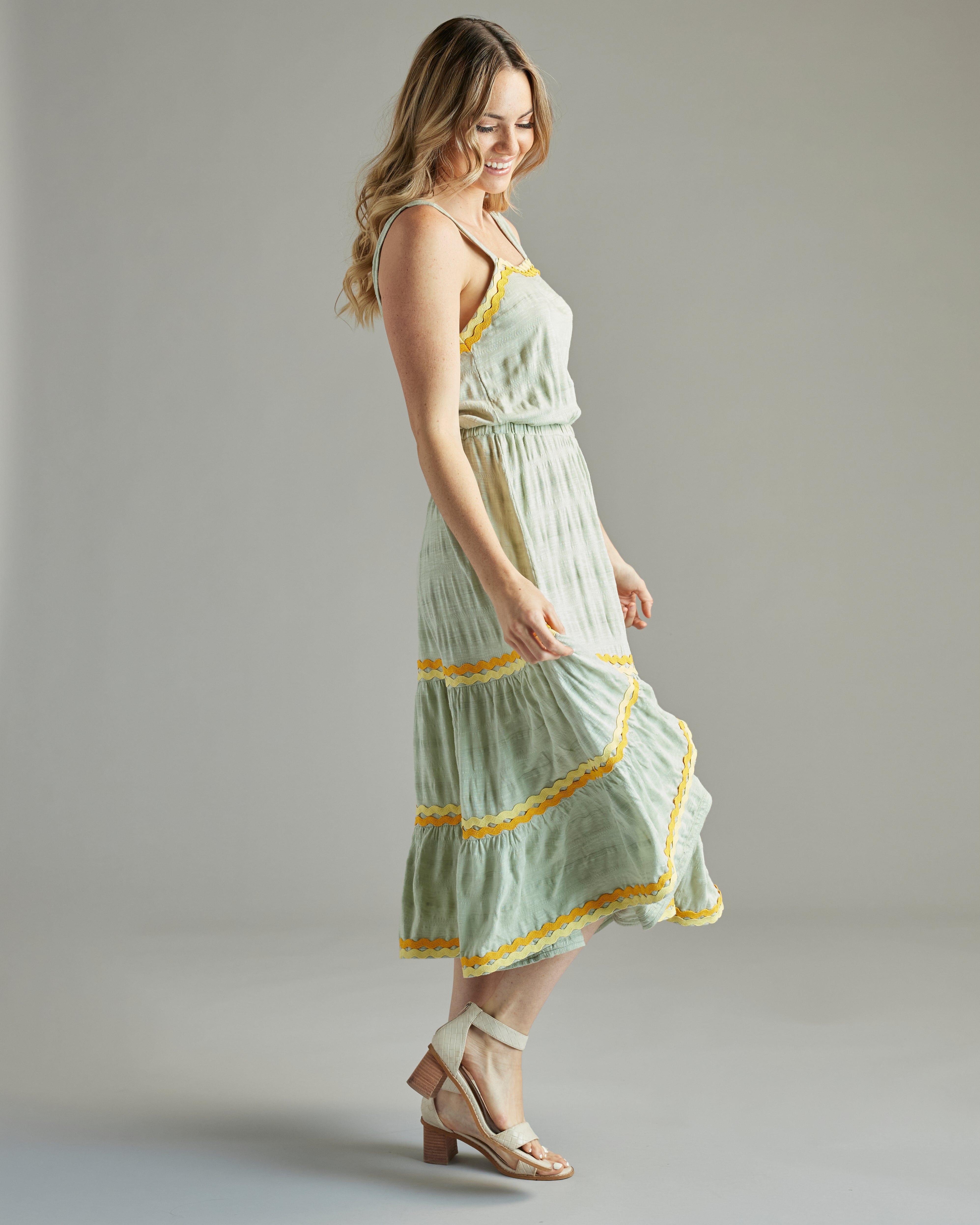 Woman in a sleeveless, midi-length green dress with orange and yellow lace accents