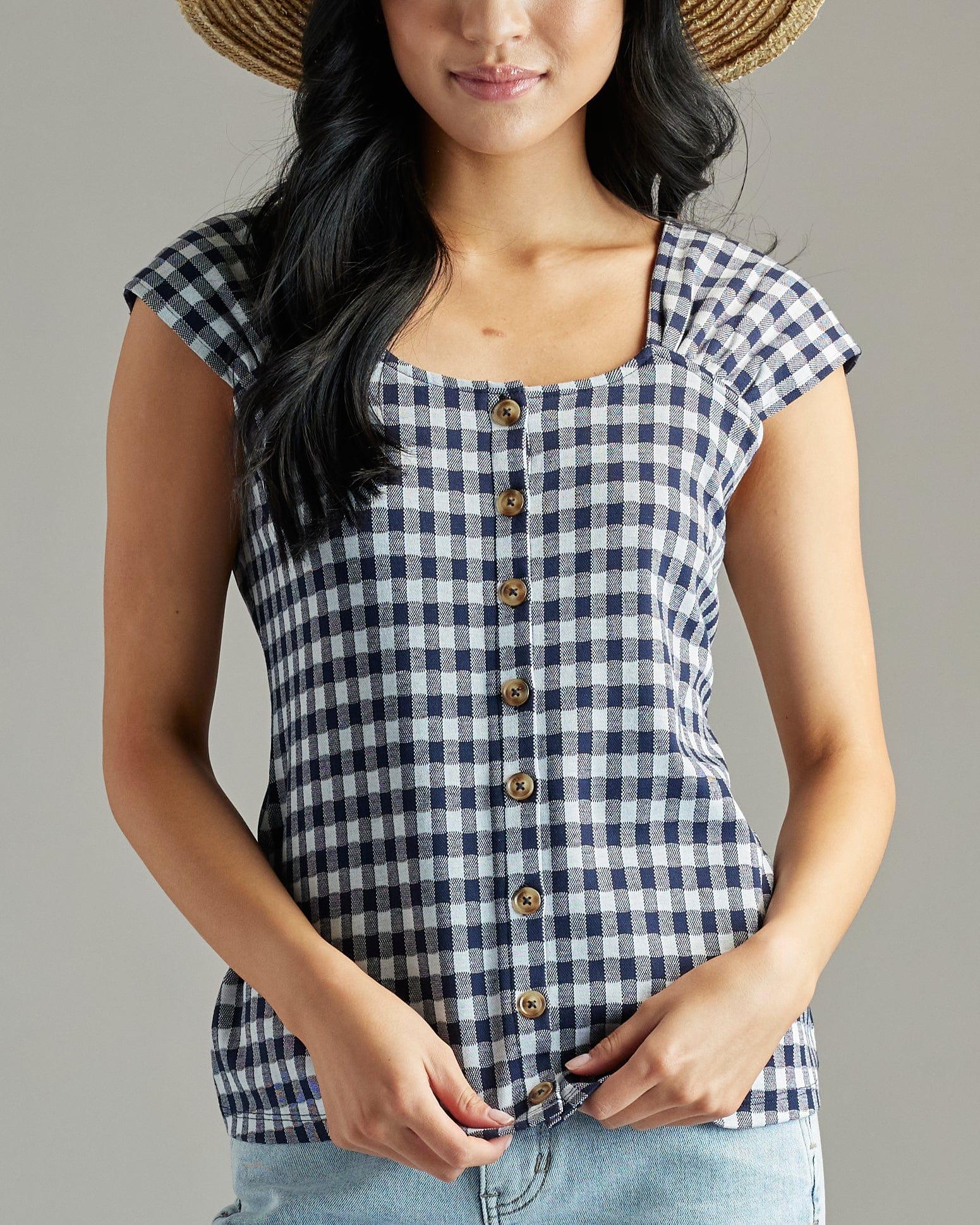 Woman in a navy and white gingham blouse with short sleeves and buttons down the front