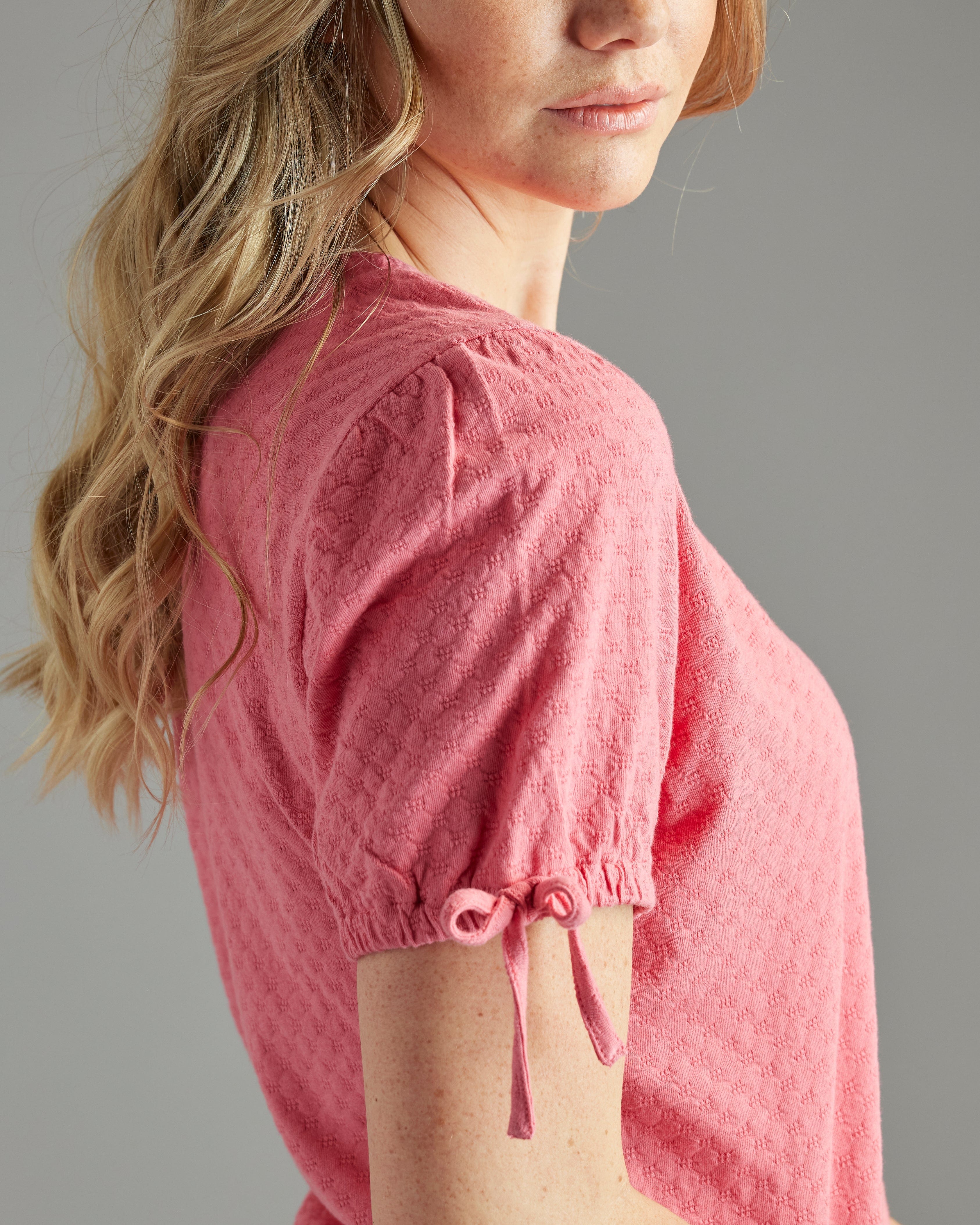 Woman in a pink, short sleeve, dotted swiss top