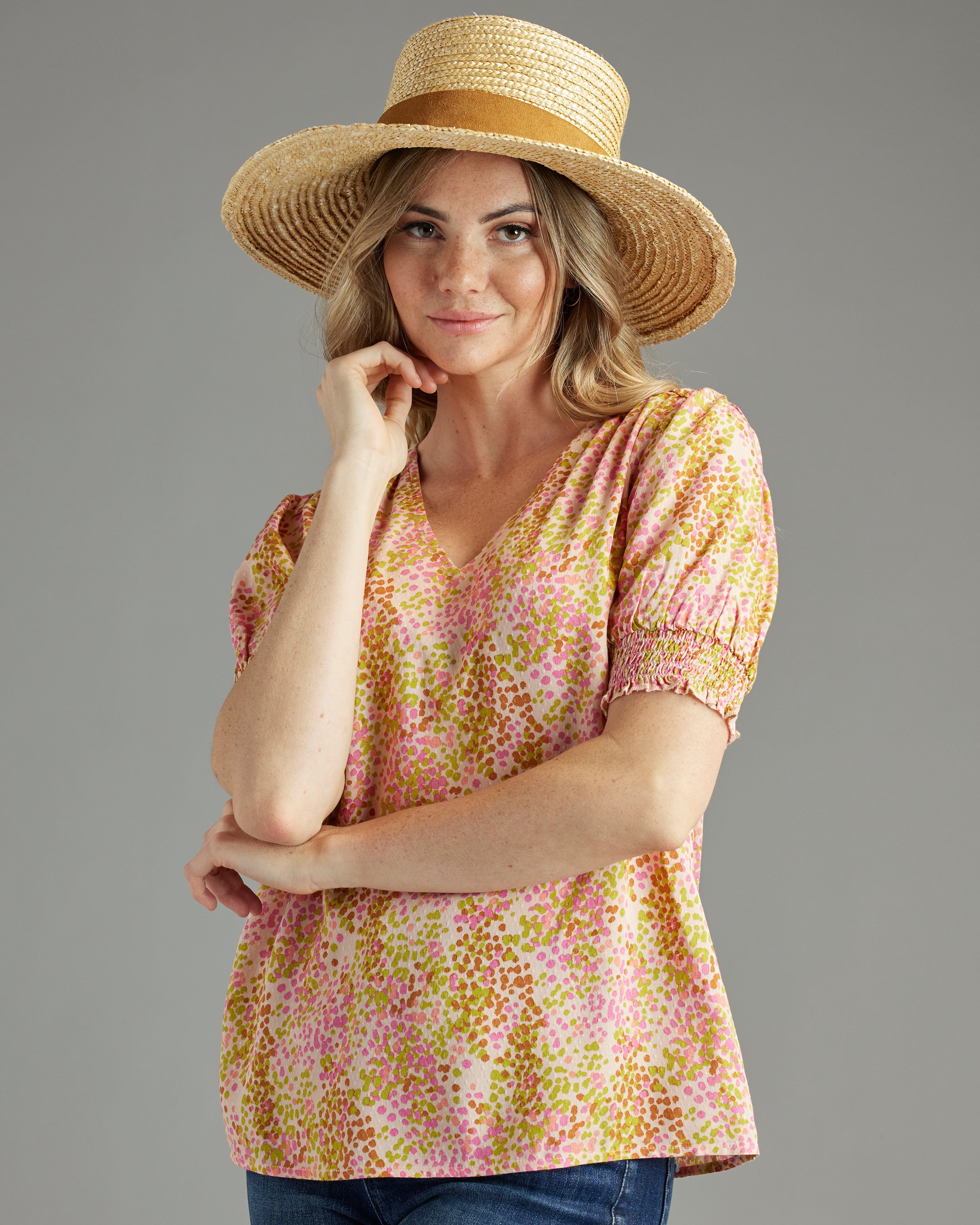 Woman in a yellow and pink print blouse with short sleeves and a v-neck