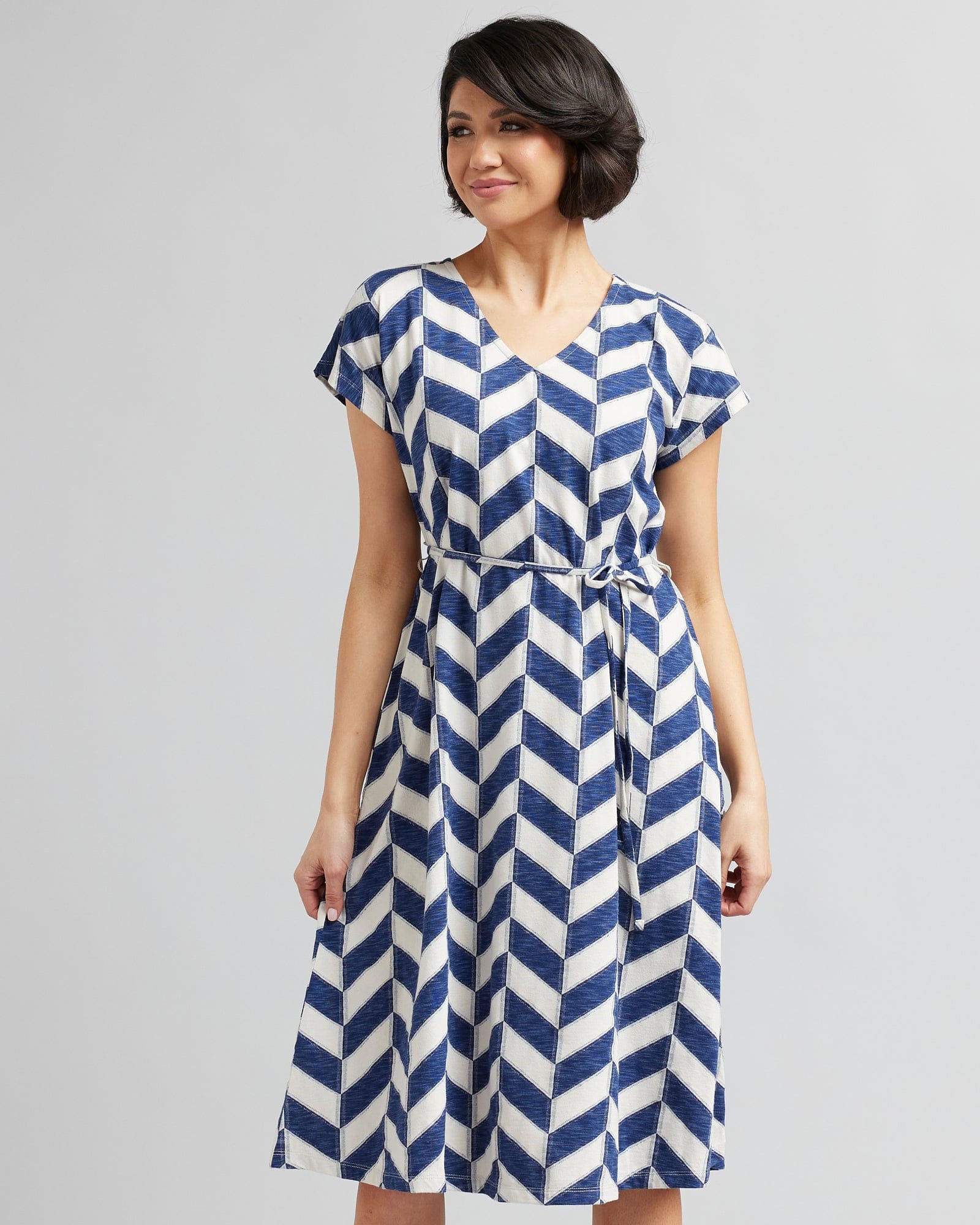 Woman in a short sleeve, midi-length, blue and white chevron patterned dress