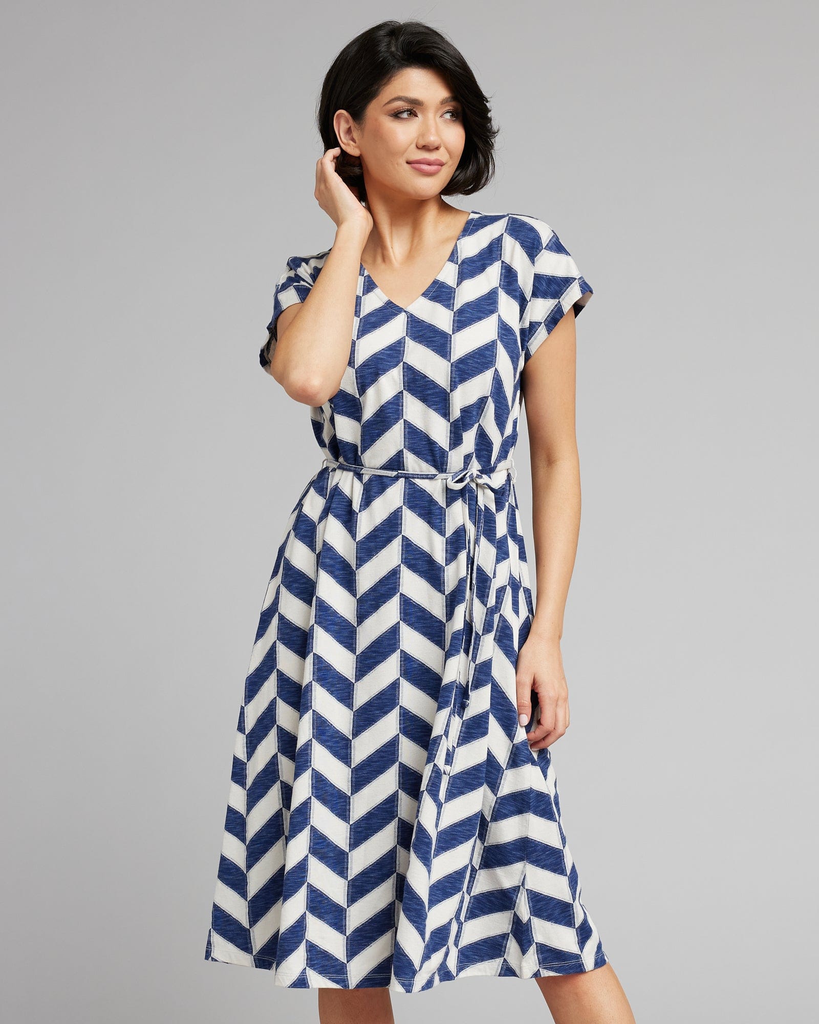 Woman in a short sleeve, midi-length, blue and white chevron patterned dress