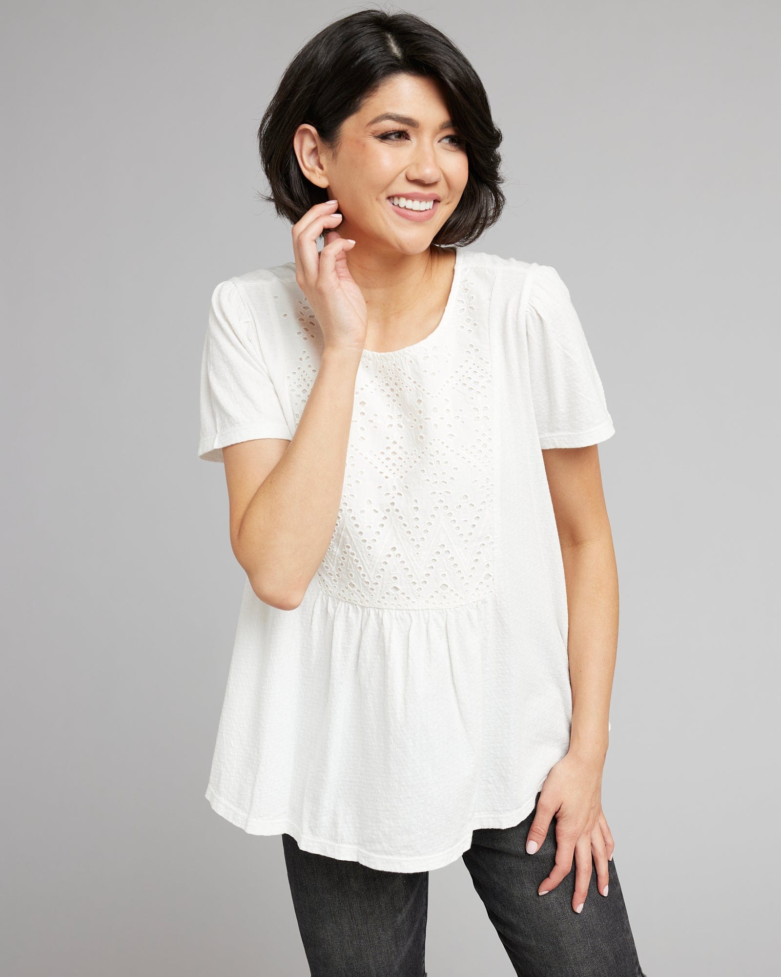 Woman in a white, short sleeved, top with eyelet motif on front