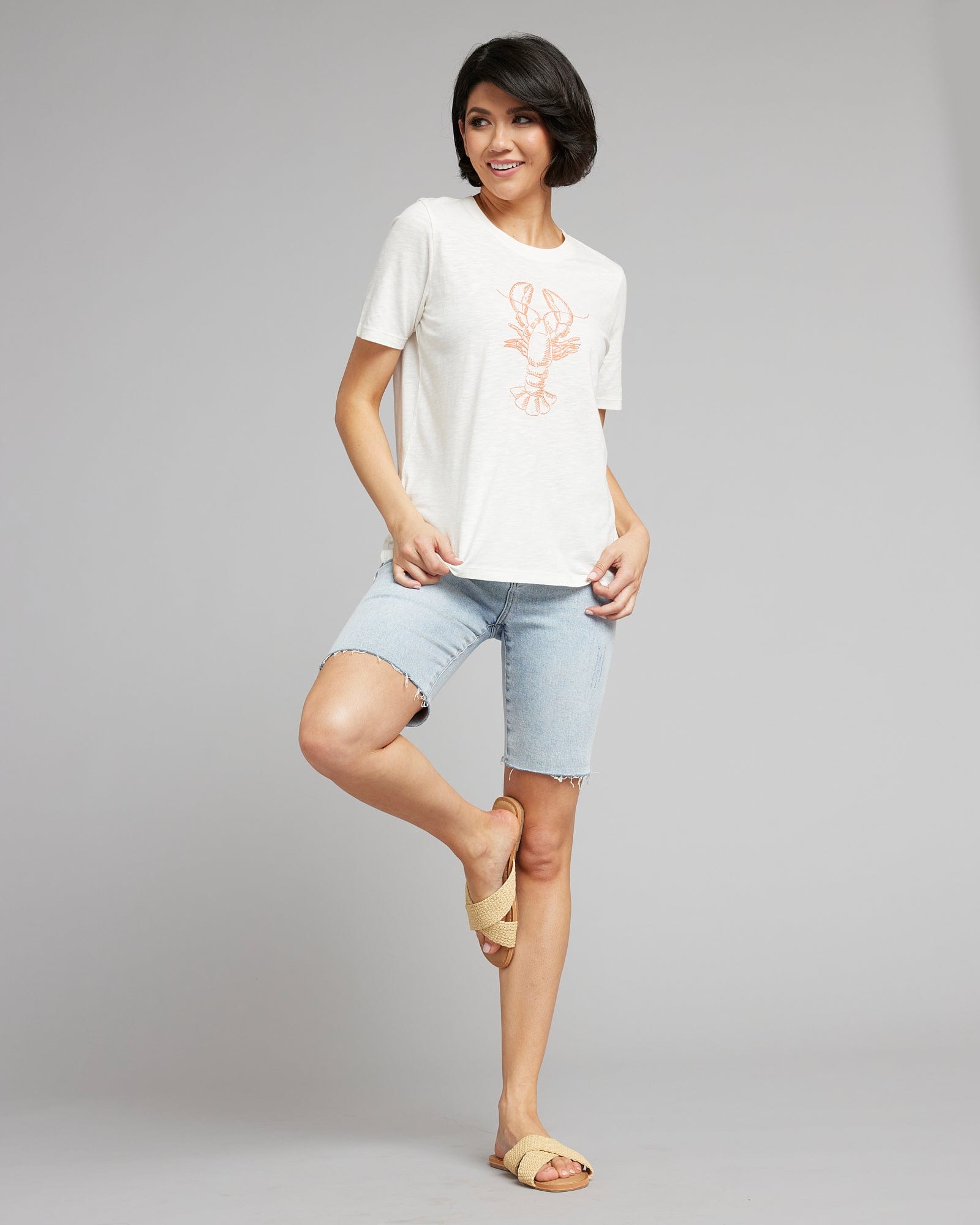 Woman in a white short sleeved graphic tee with a lobster on the front