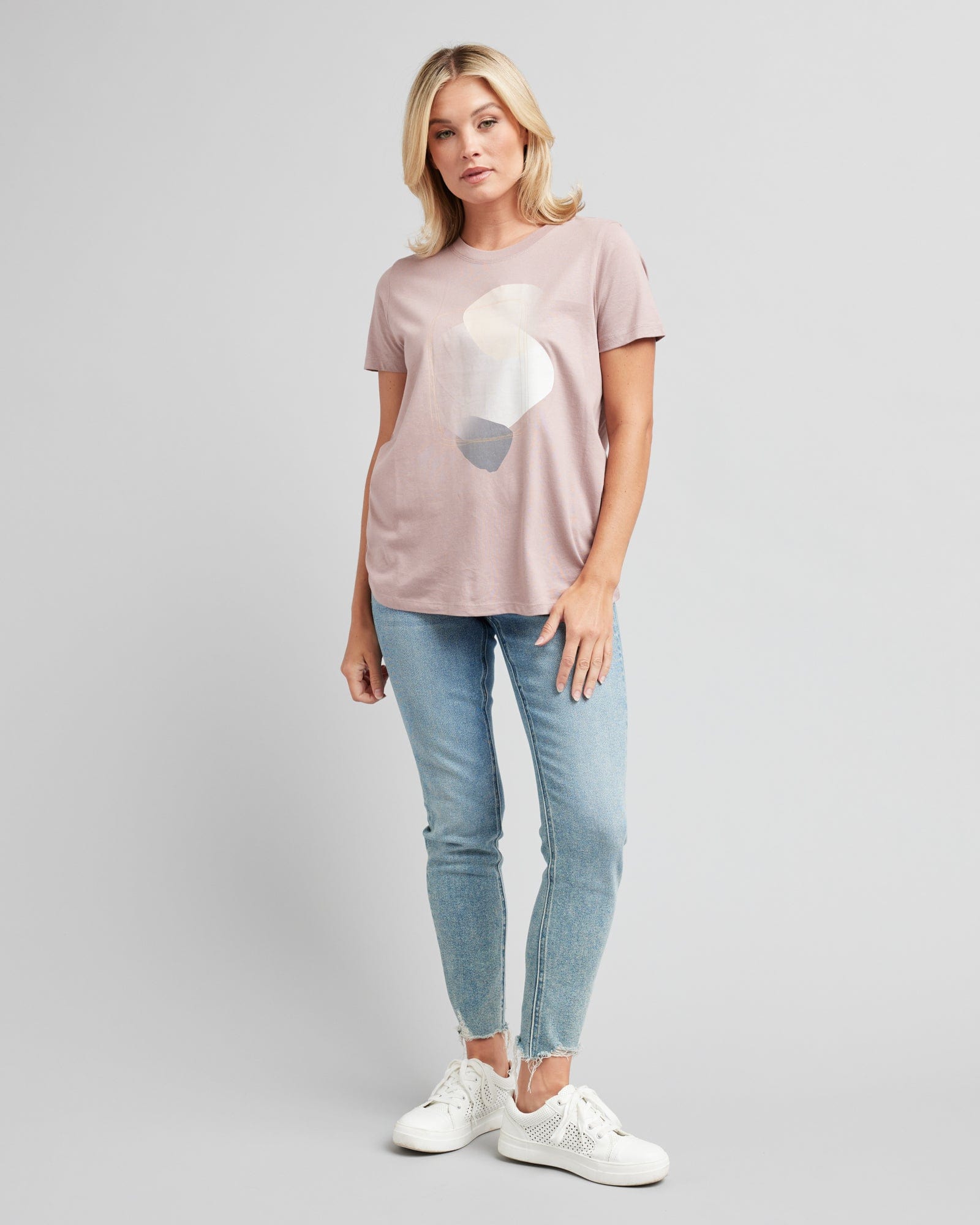 Woman in a short sleeve, pink graphic tee with a silver design on front