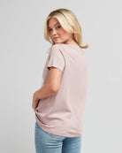 Woman in a short sleeve, pink graphic tee with a silver design on front