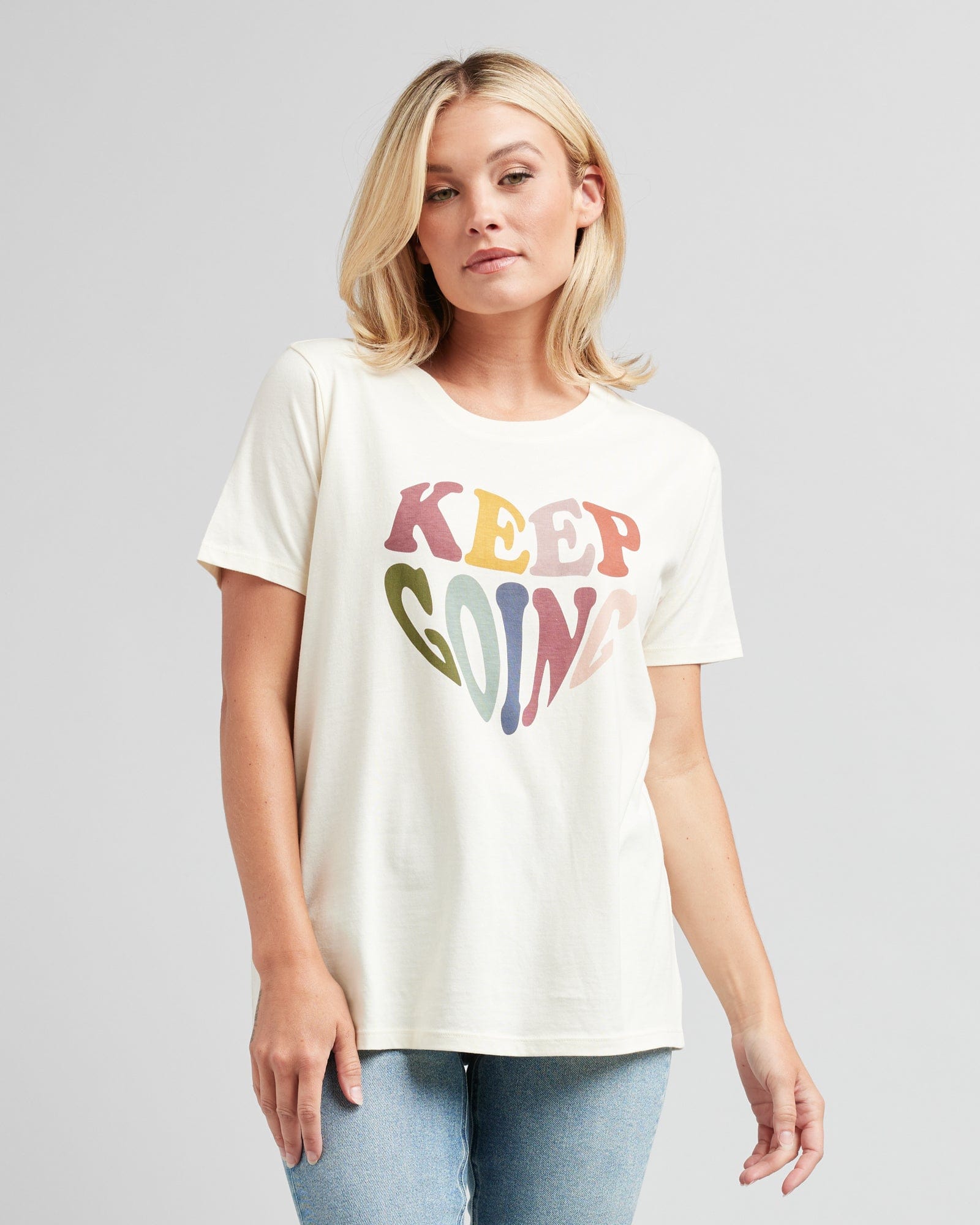 Woman in a short sleeve, white graphic tee that says "Keep Going"
