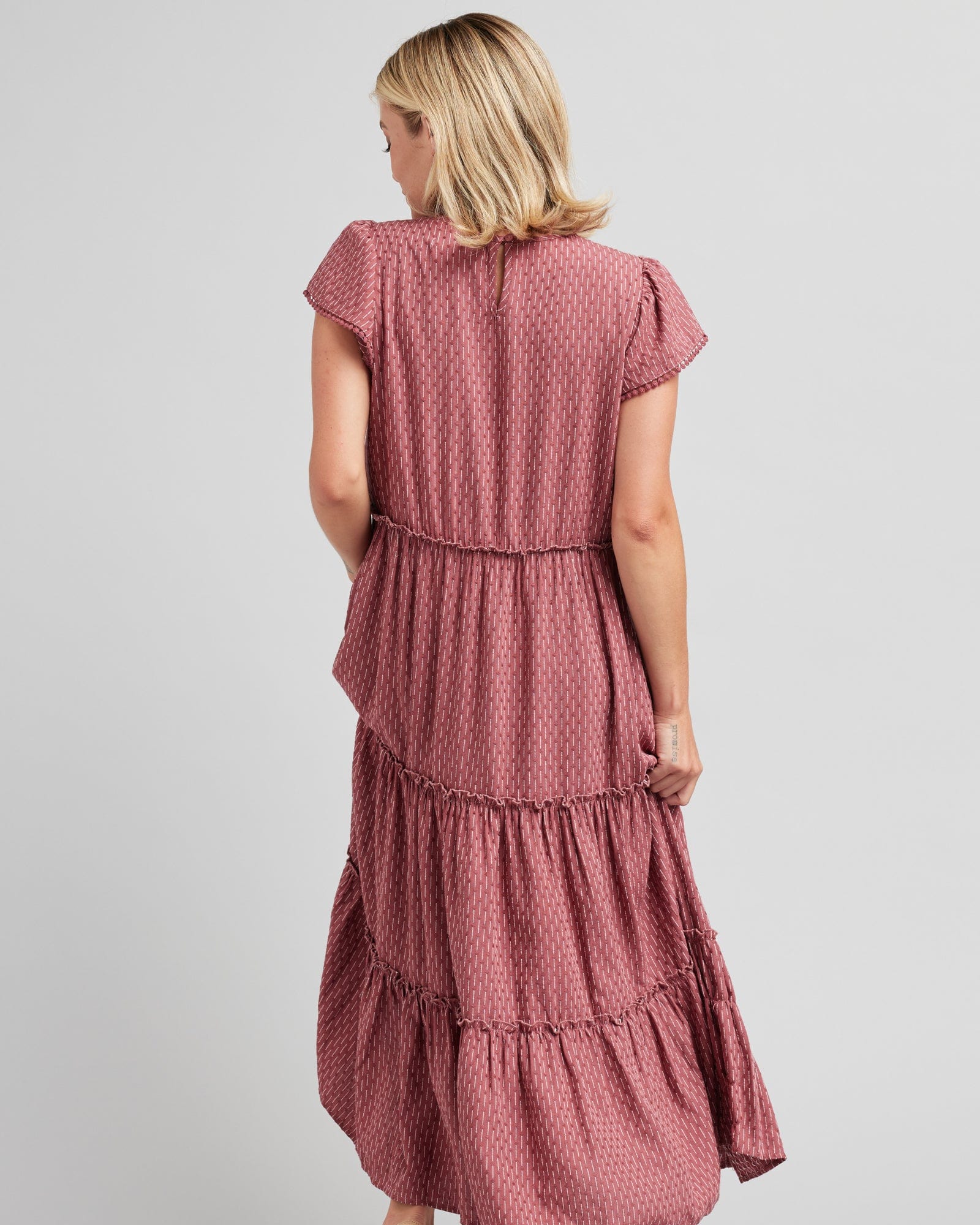 Woman in a short sleeve, midi-length, tiered skirt, pink dress