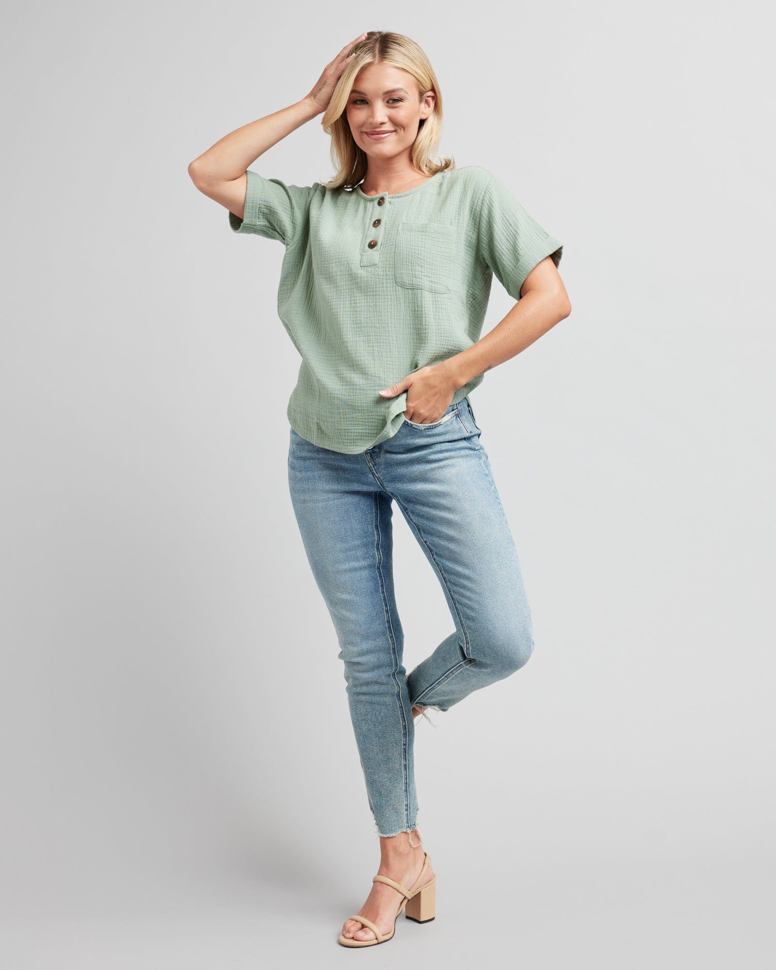 Woman in a short cuffed sleeve blouse with buttons at neckline and a front pocket