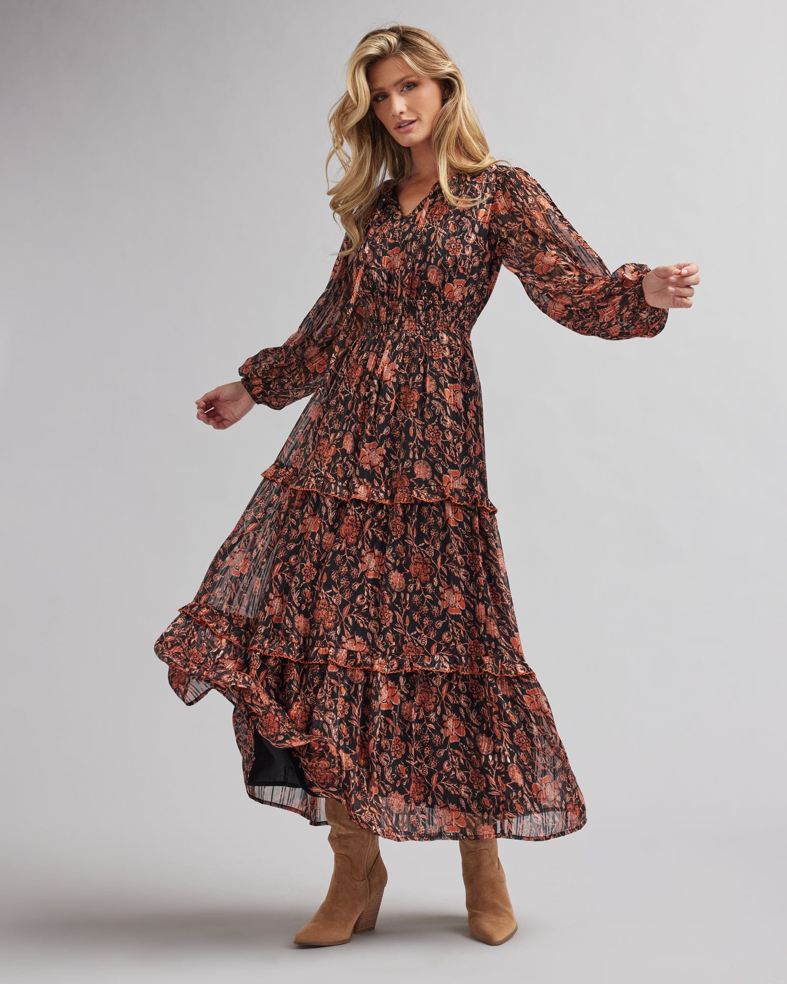 Woman in a long sleeve, maxi length, black and orange floral print dress
