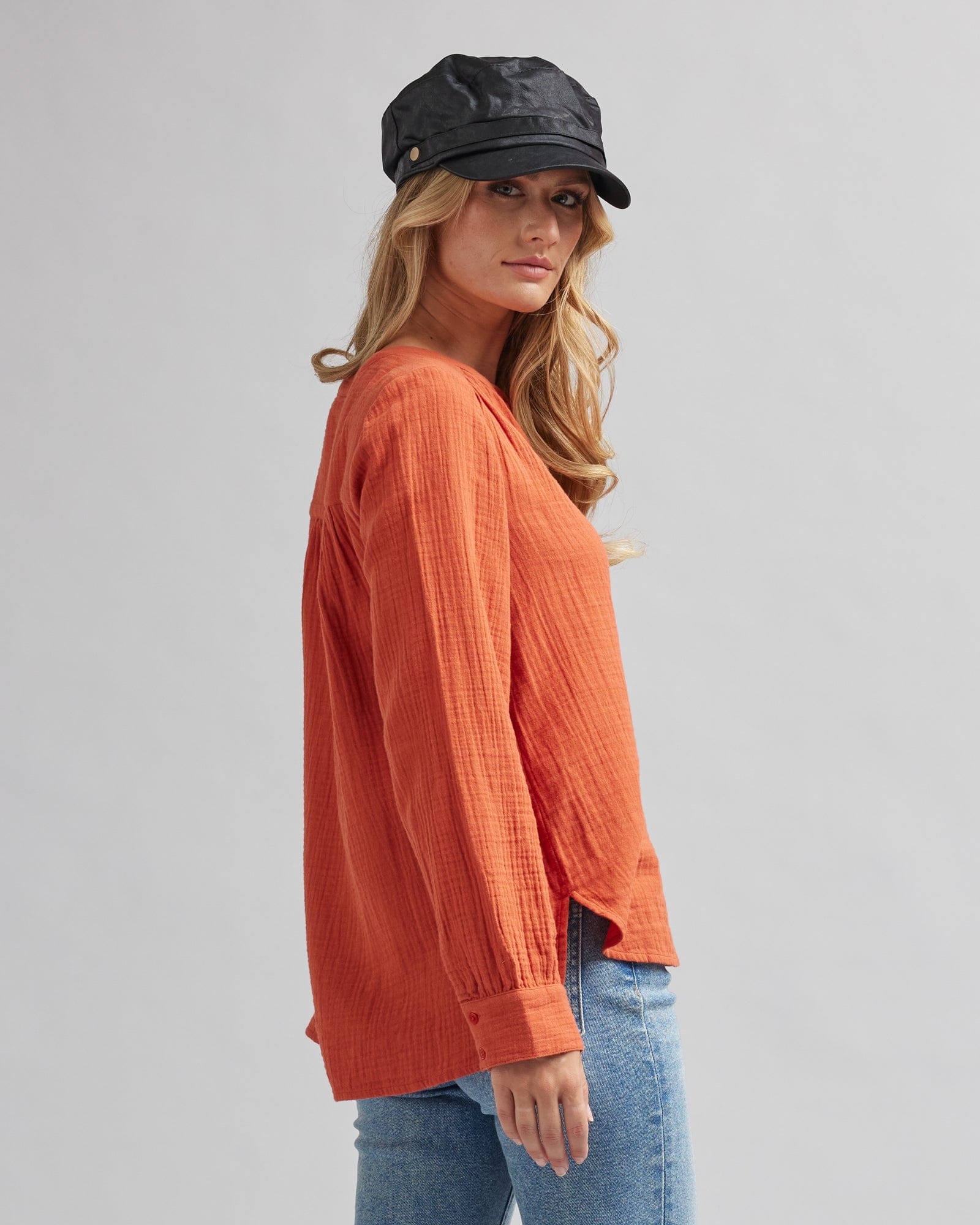 Woman in a long sleeve, orange, textured blouse