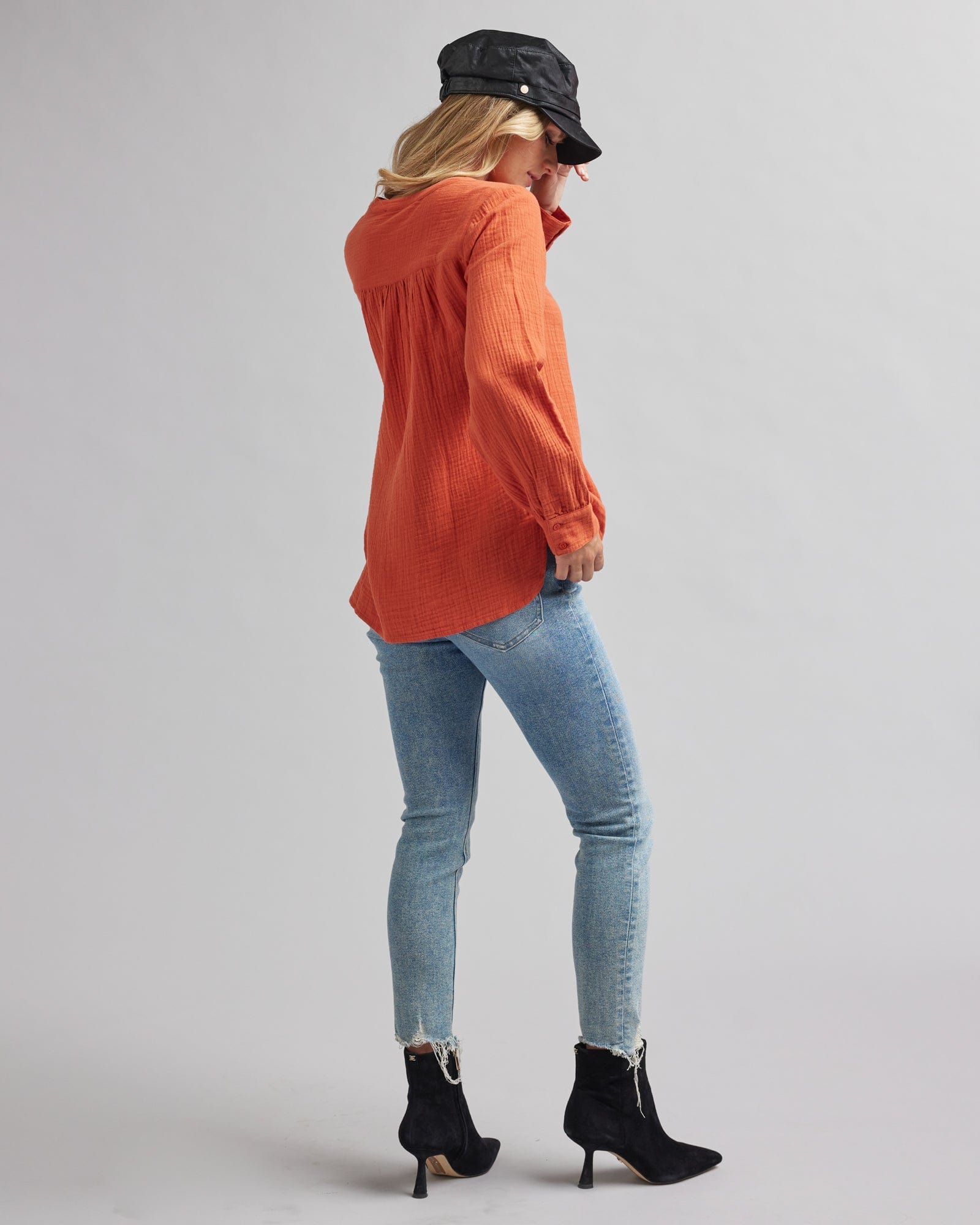 Woman in a long sleeve, orange, textured blouse