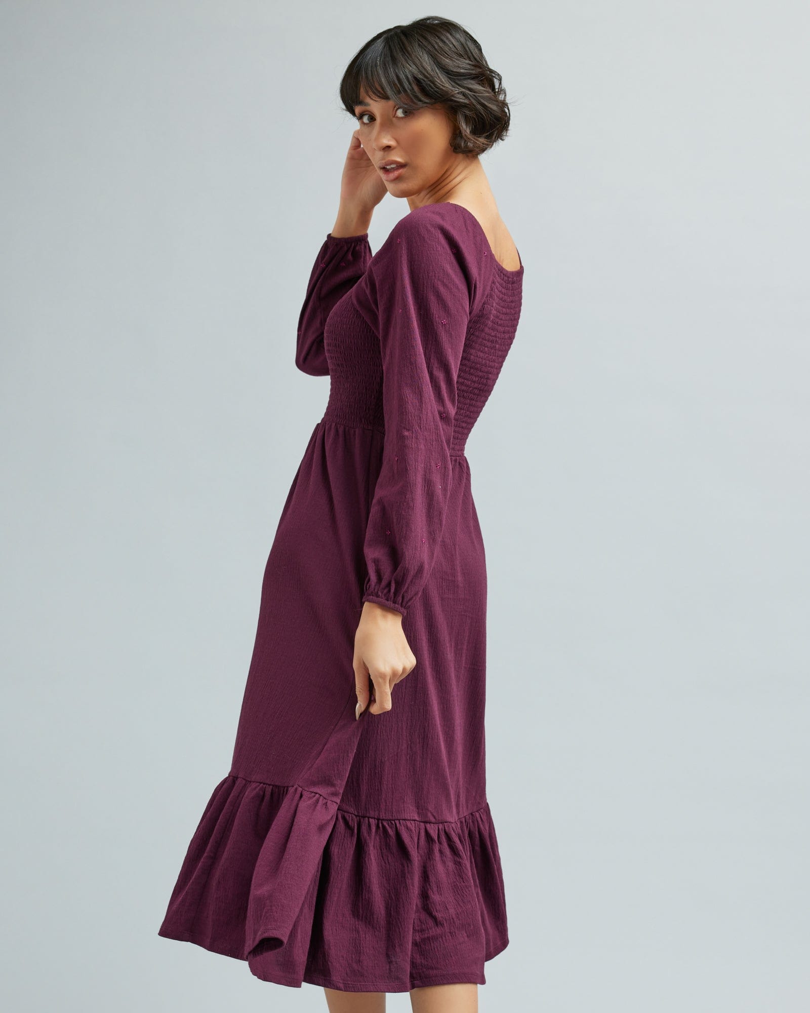 Woman in a long sleeve, smocked bodice, purple dress