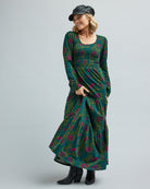 Woman in a long sleeve, tiered maxi dress with orange and green floral print