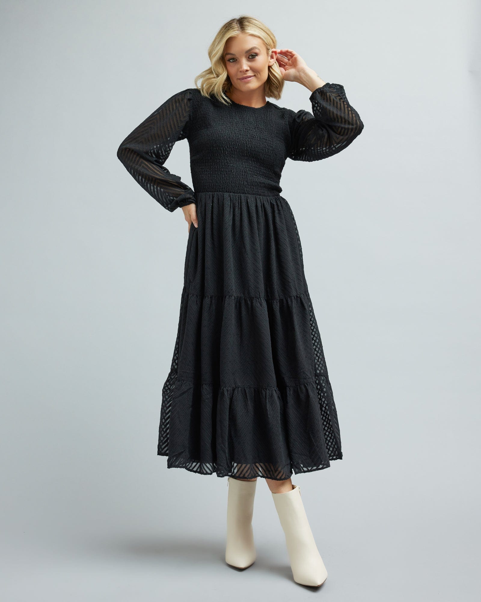 Woman in a long sleeve, smocked, tiered skirt dress