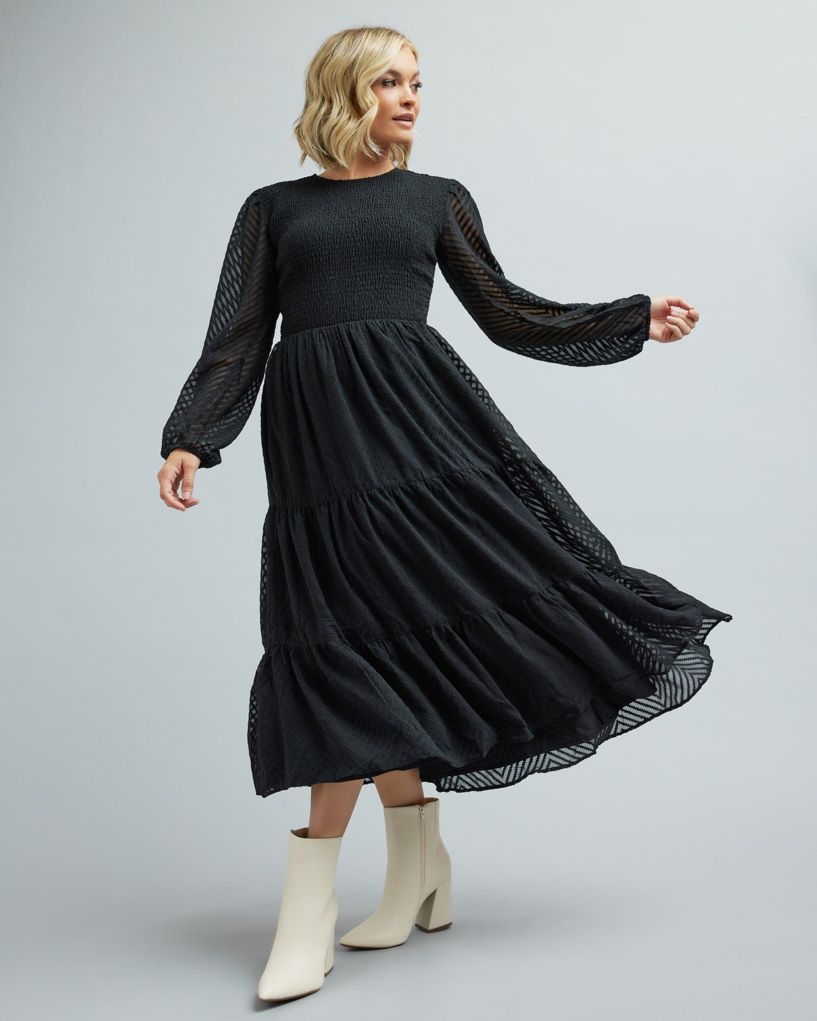 Woman in a long sleeve, smocked, tiered skirt dress