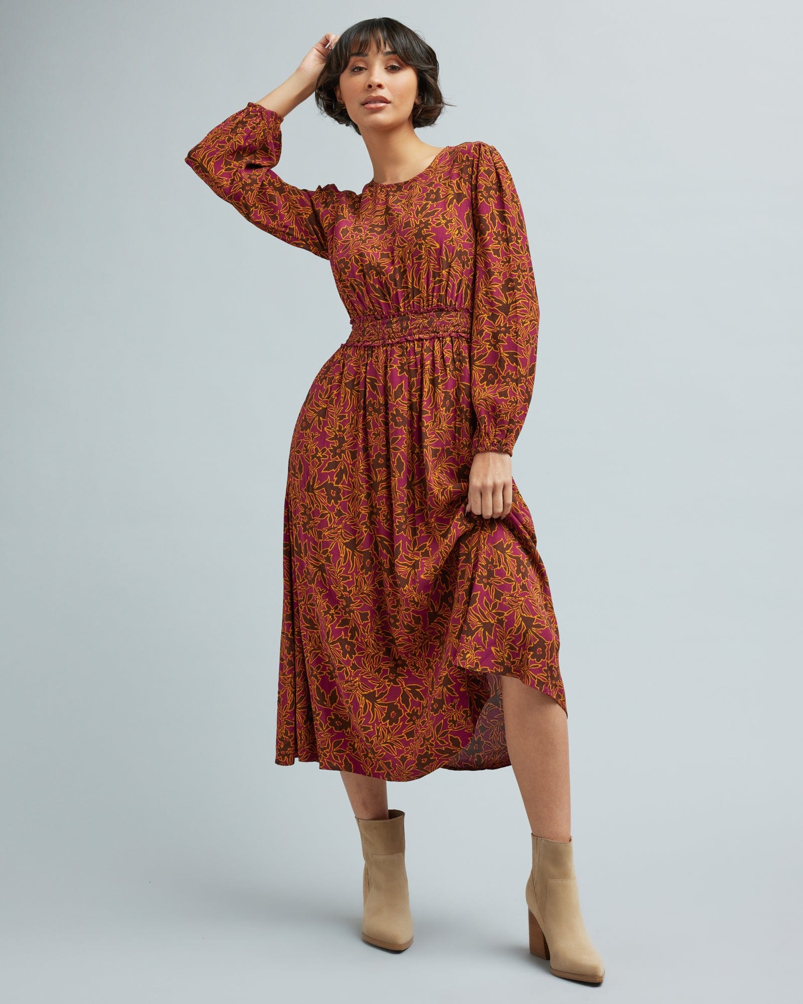 Woman in a long sleeve, brown and orange floral print dress