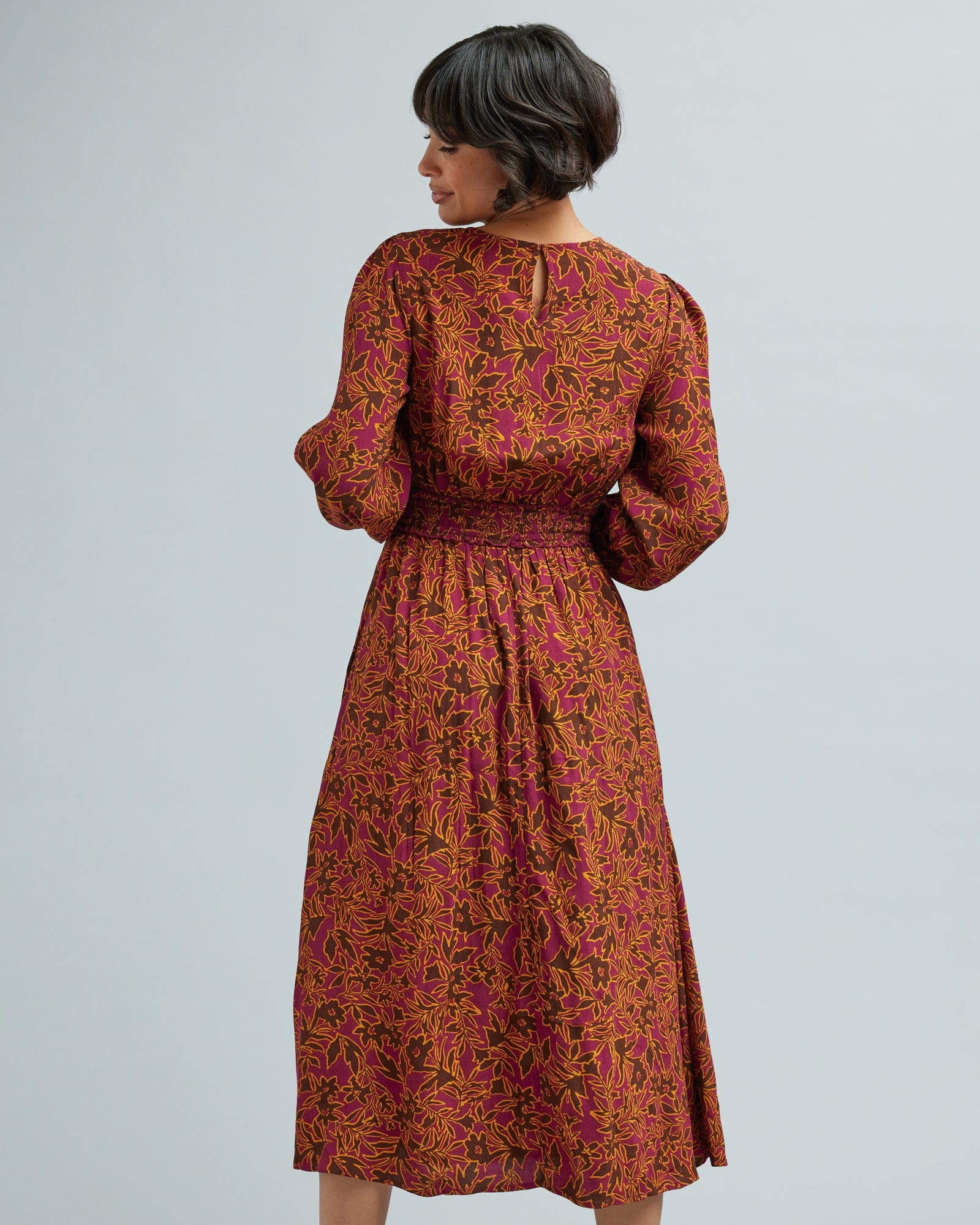 Woman in a long sleeve, brown and orange floral print dress