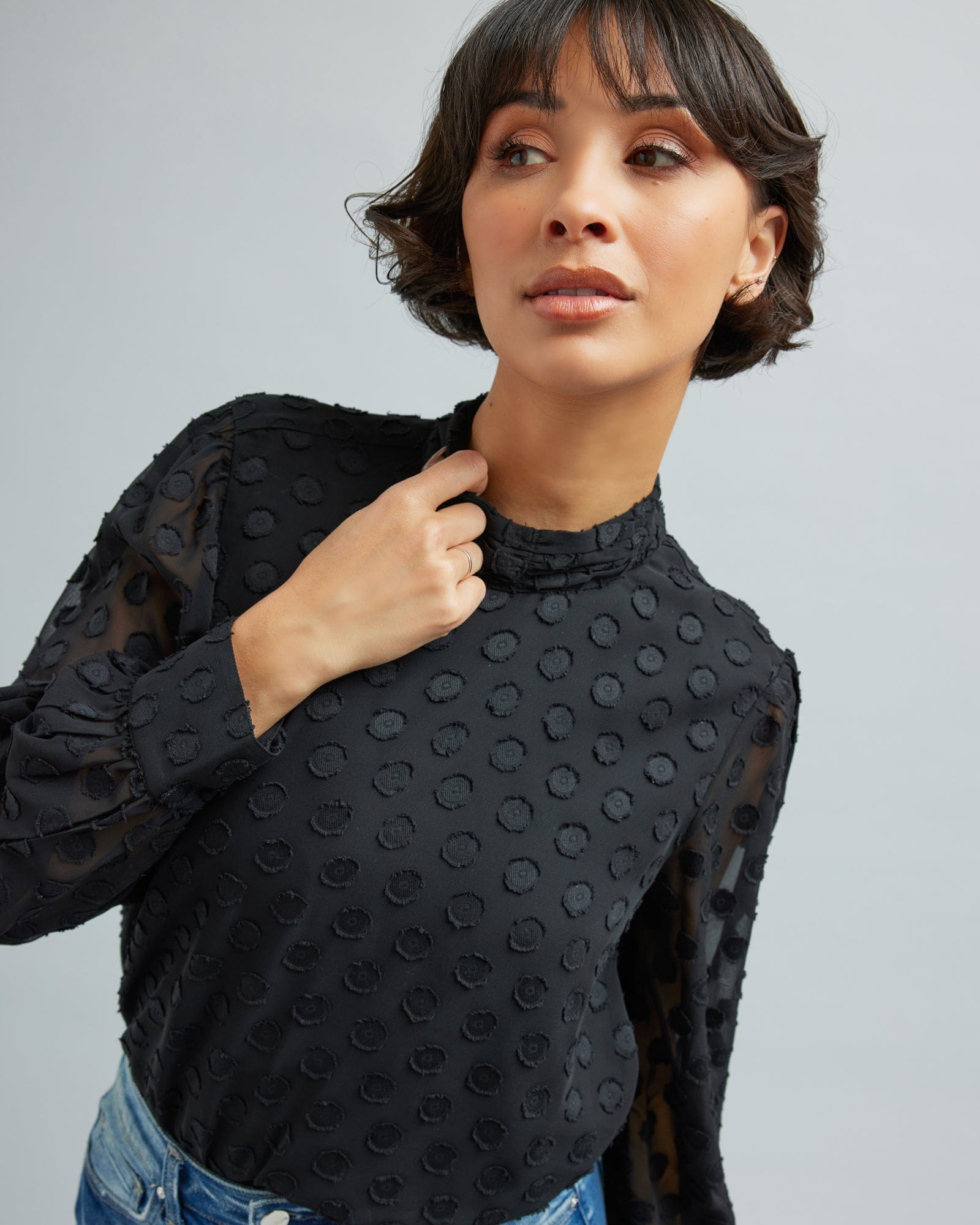 Woman in a long sleeve, black, blouse with polka dots